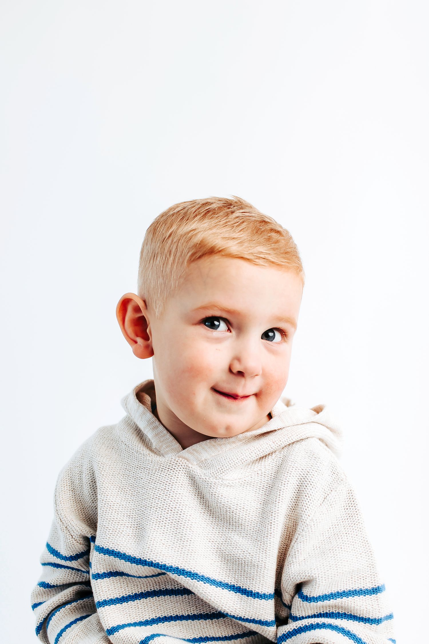 A young child in a white and blue striped sweater poses playfully in a sequence of photos.