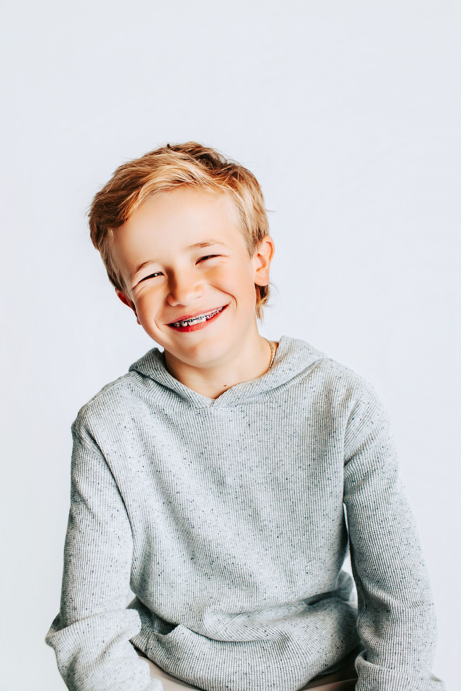 A child in a grey sweatshirt shown in multiple playful poses against a white backdrop.
