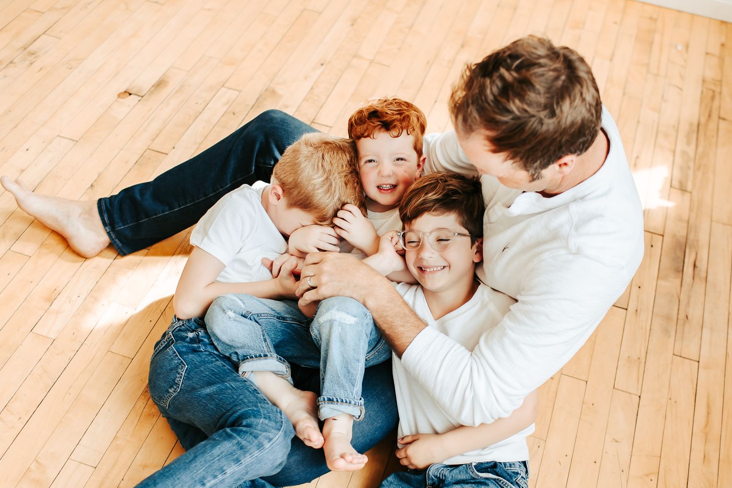 Candid family photos on wooden floor showing playful interaction.