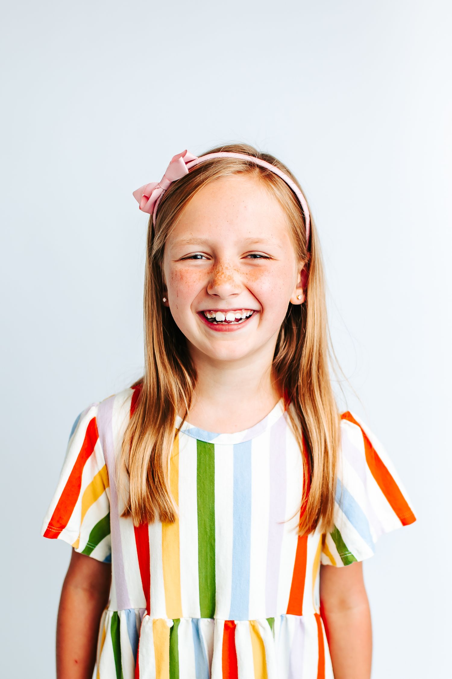 Bright expressions in a colorful striped dress with hair accessories.