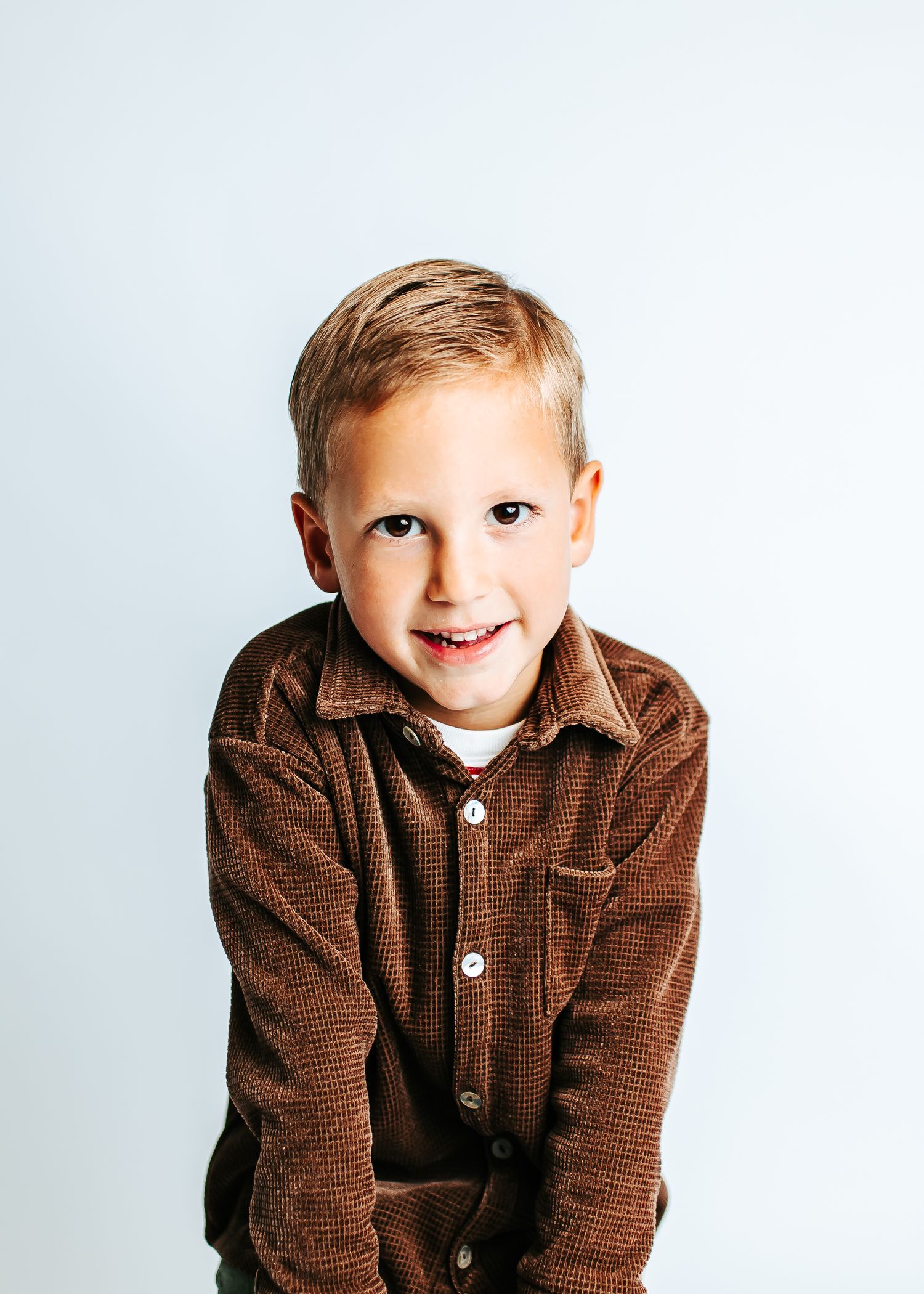 Expressive poses wearing a brown corduroy jacket against a white backdrop.