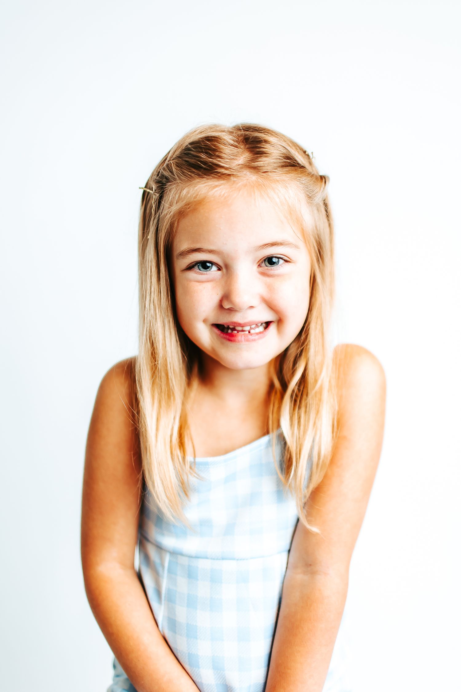 Studio portraits in light blue gingham dress showing cheerful expressions.