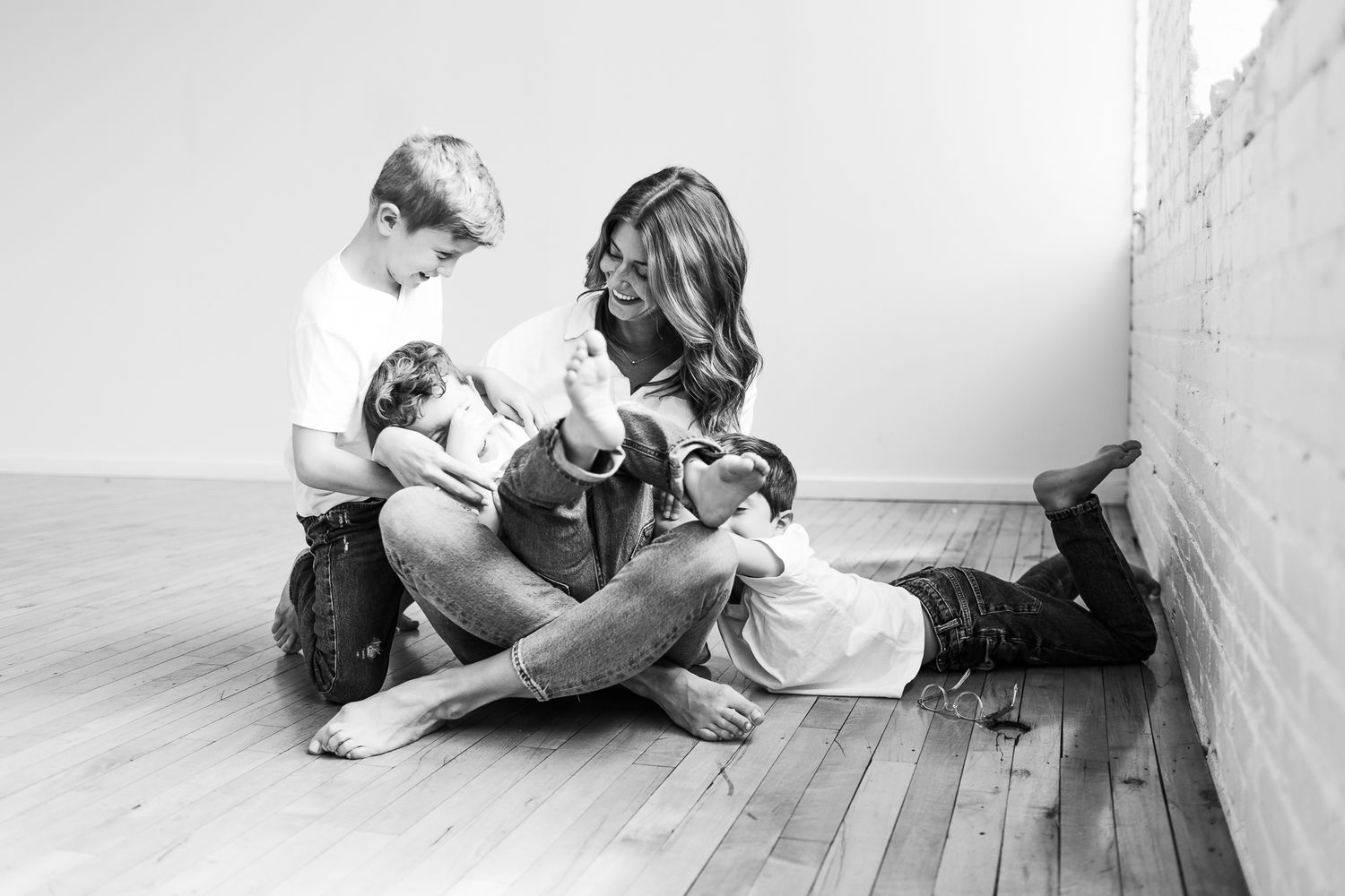 Black and white photo series showing intimate family moments on wooden floor.