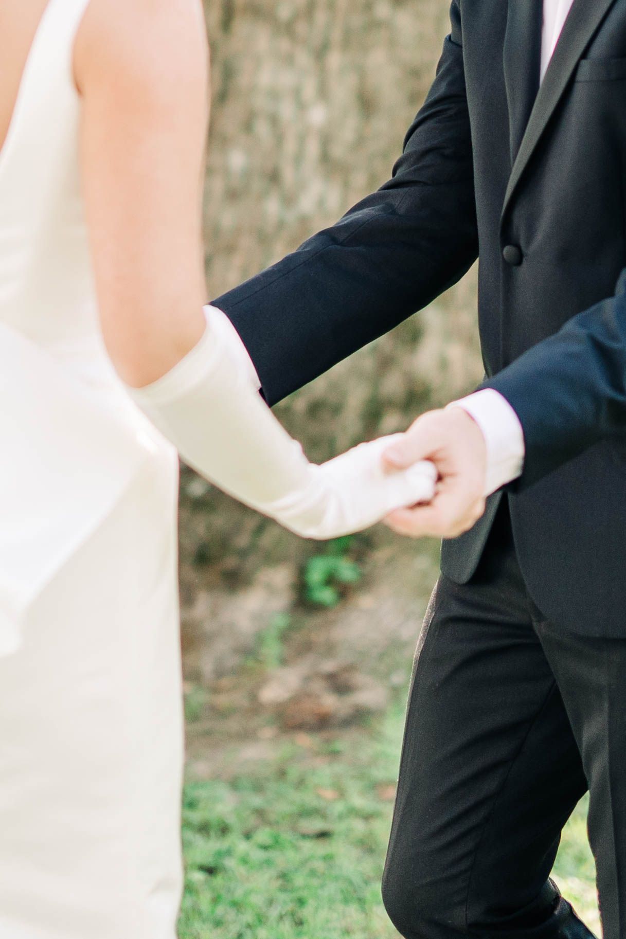 Elegant wedding attire detail showing black tuxedo and white dress.