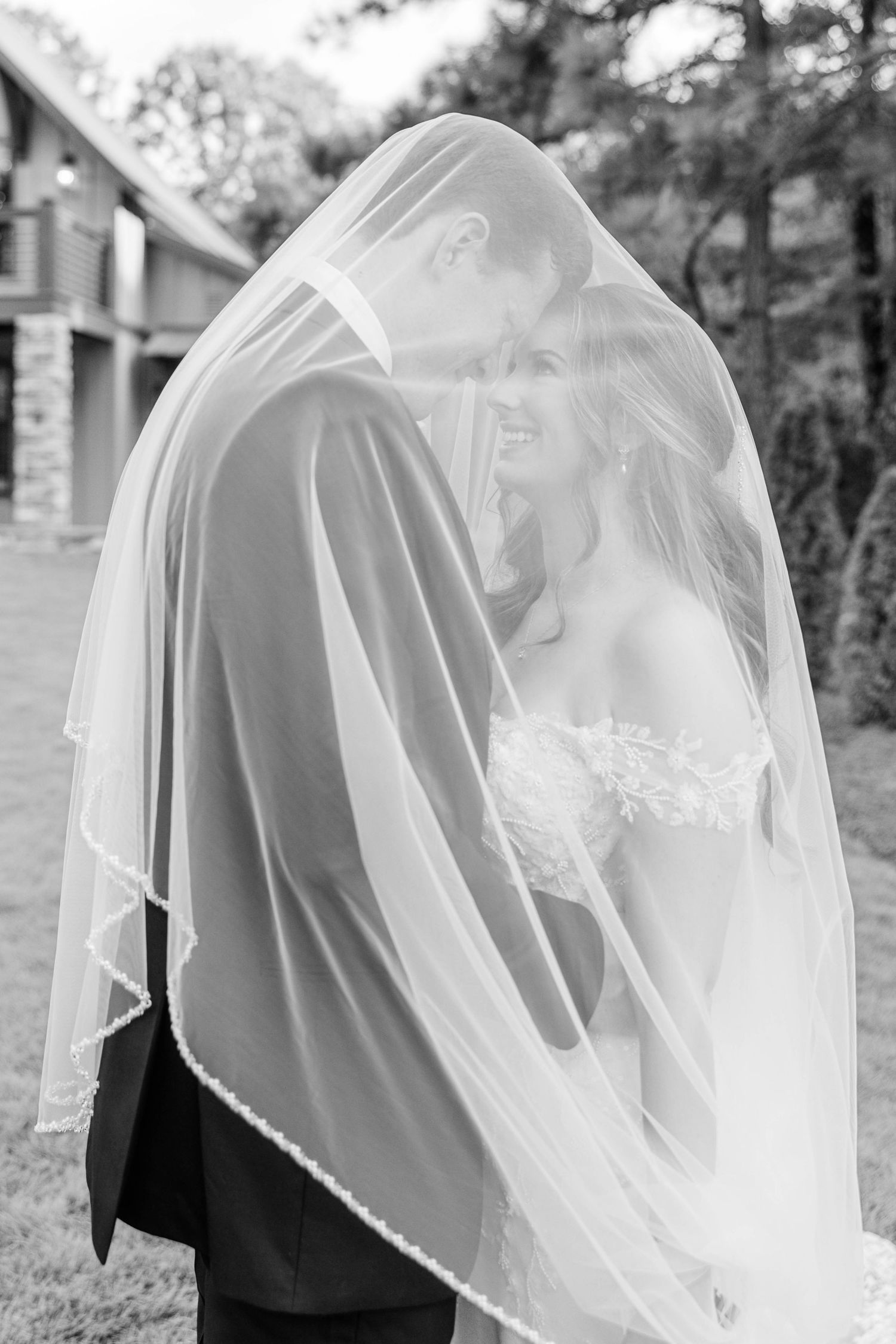 Romantic black and white photo of a flowing bridal veil catching the breeze outdoors.