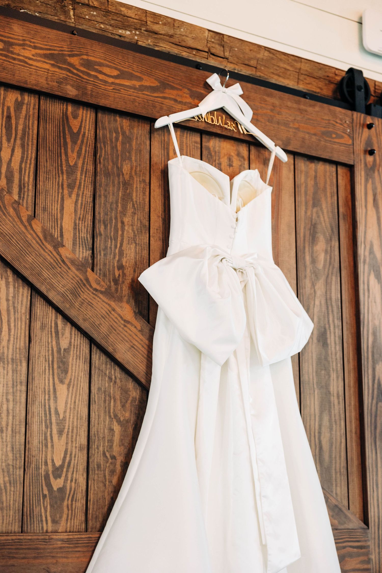 White wedding dresses hanging on wooden barn doors creating an elegant rustic display.