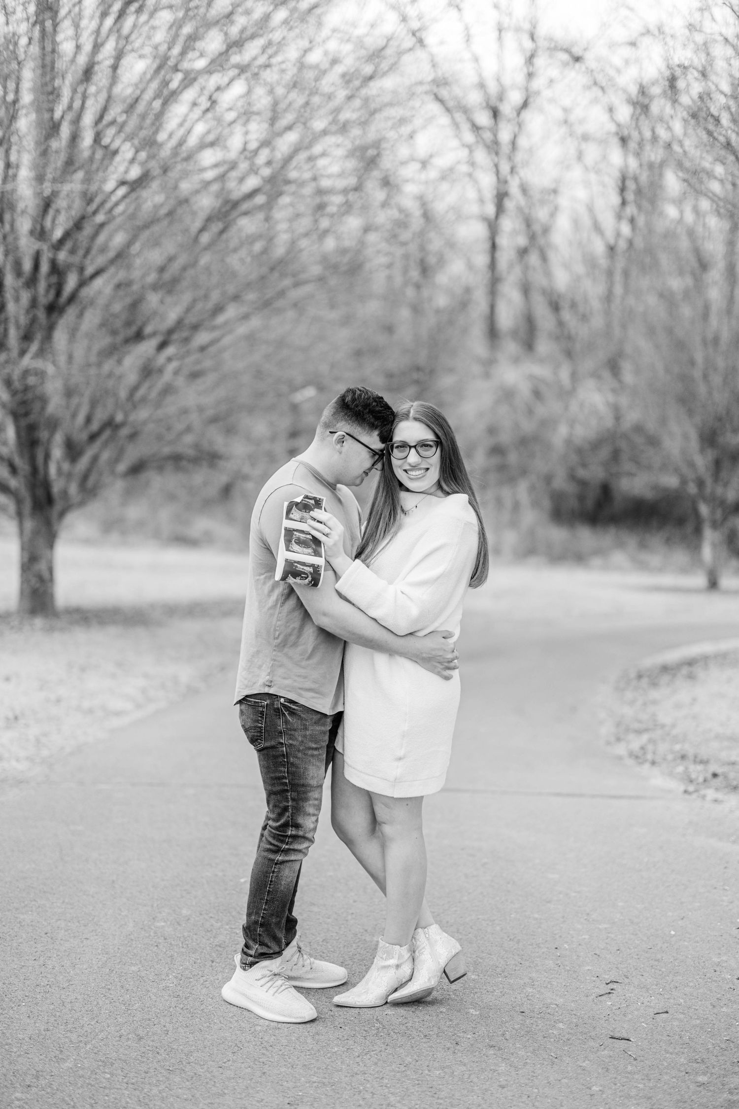 Black and white engagement photo on a park path.