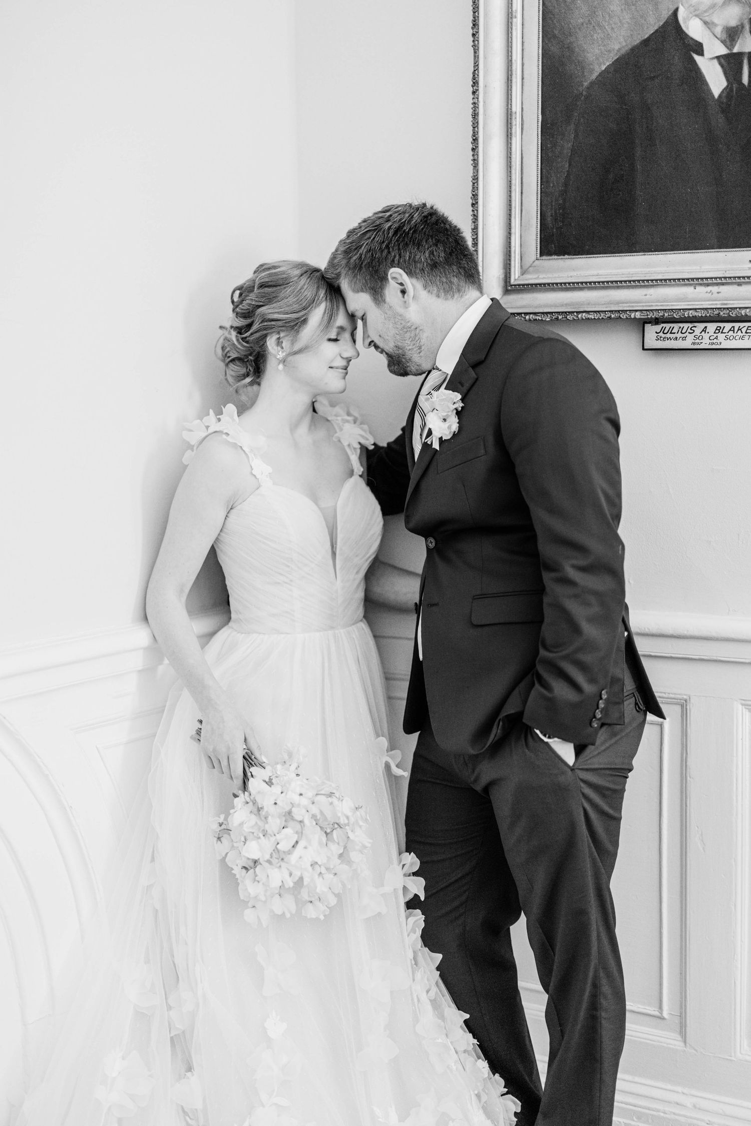 An intimate black and white wedding portrait showing a tender moment between newlyweds.