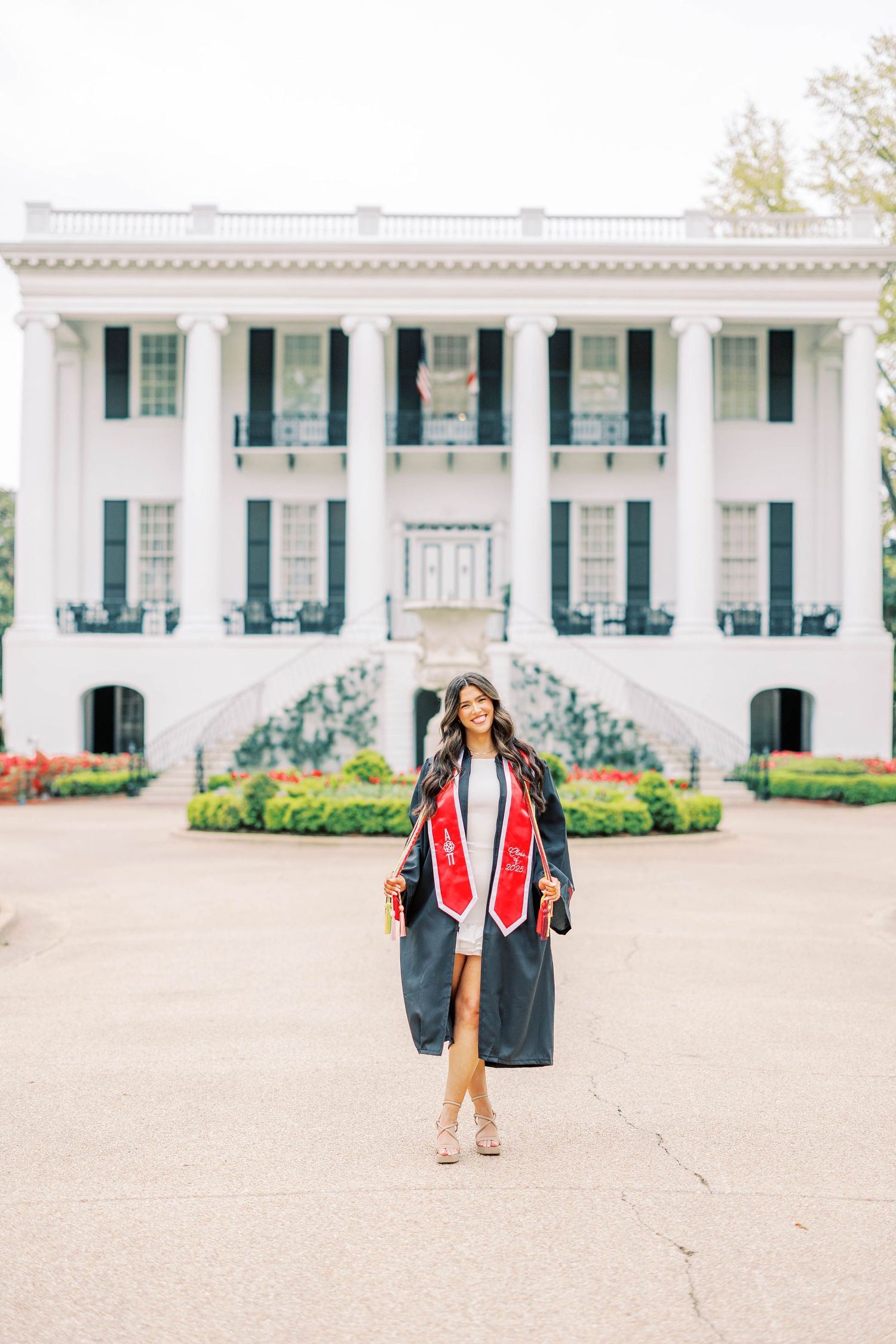 White colonial style building with columns and blue shutters in background of graduation photos.