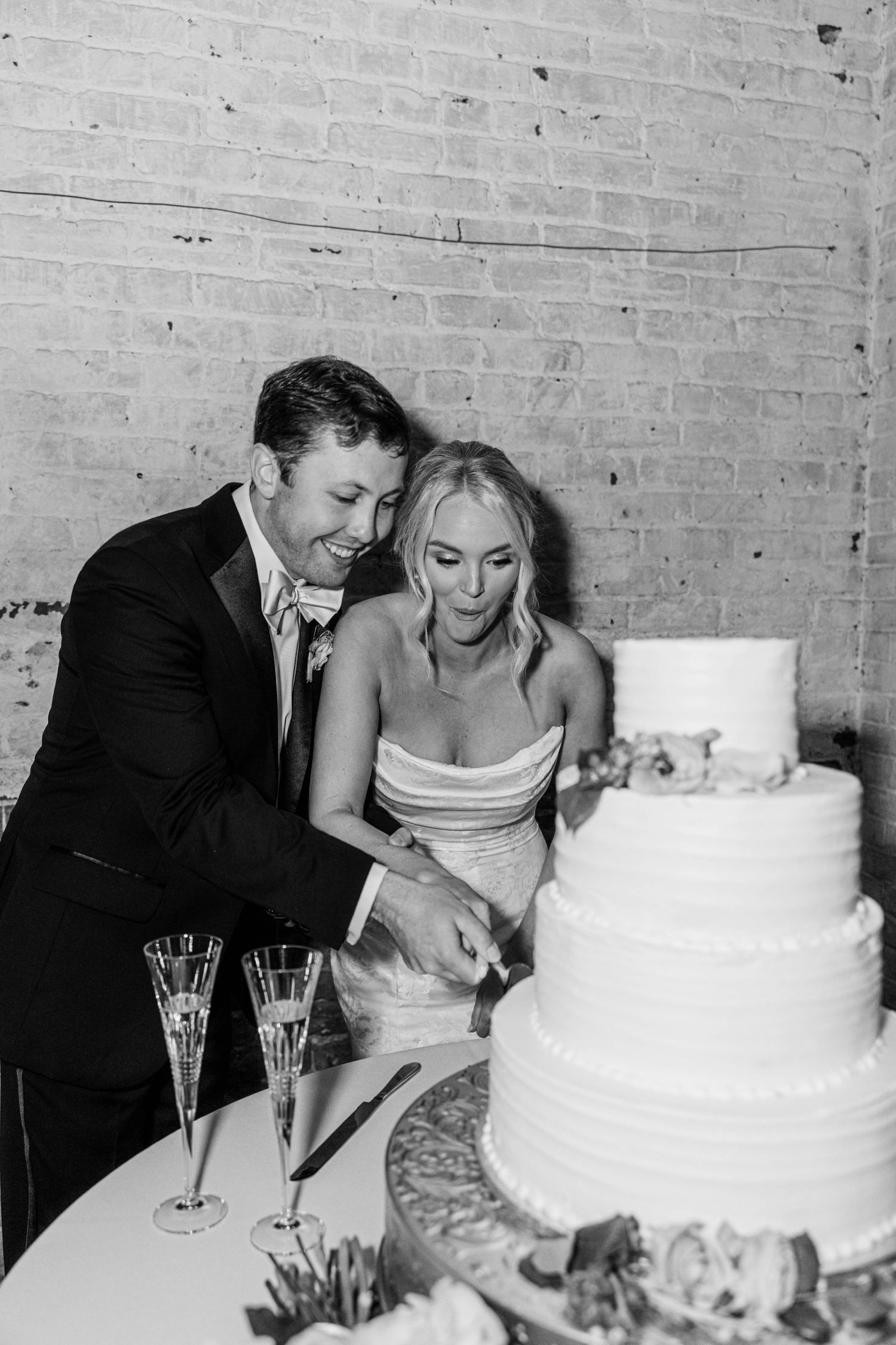 Black and white sequence of newlyweds cutting their classic white tiered wedding cake.
