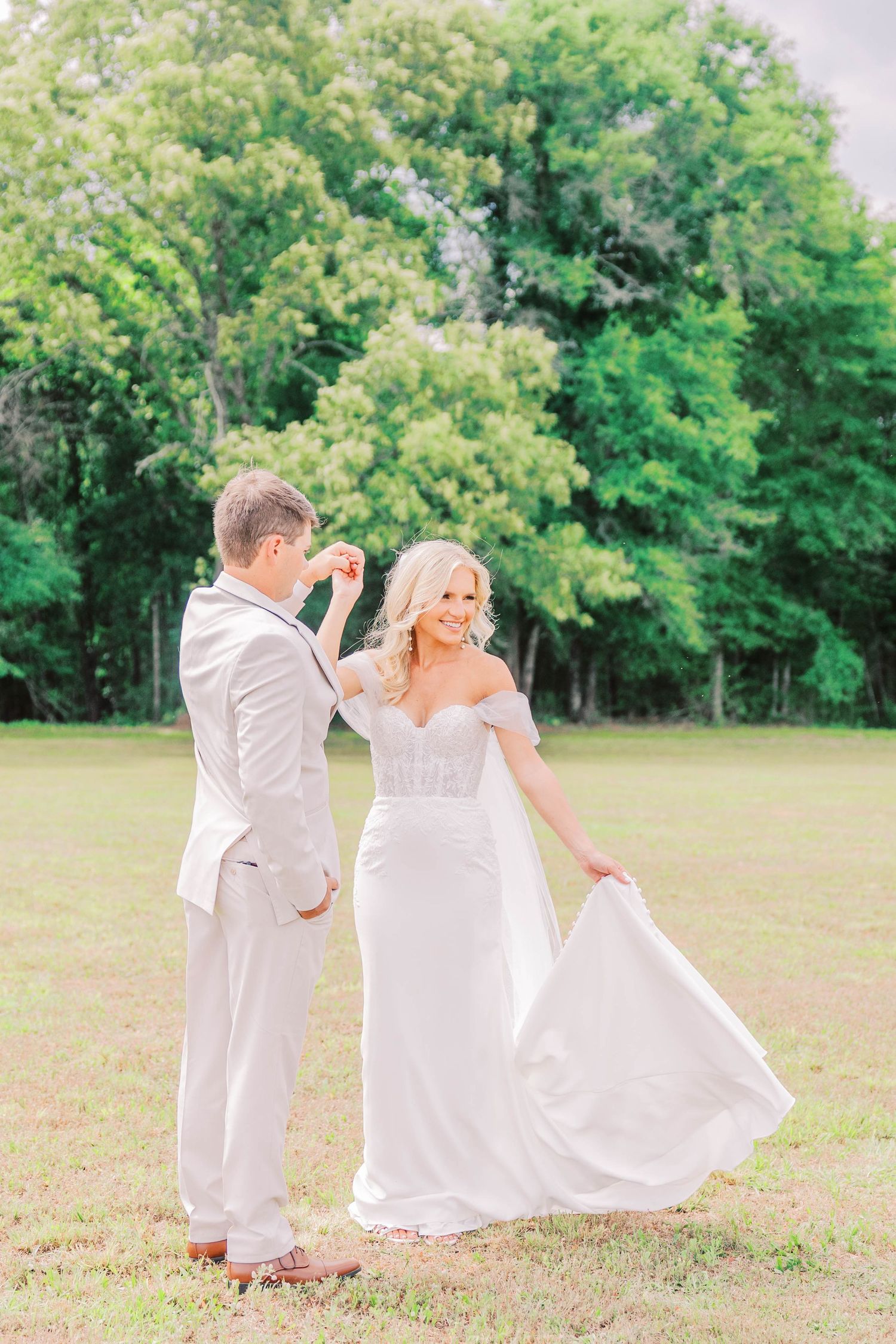 A candid wedding moment on a lush green lawn with couple in light-colored formal attire.