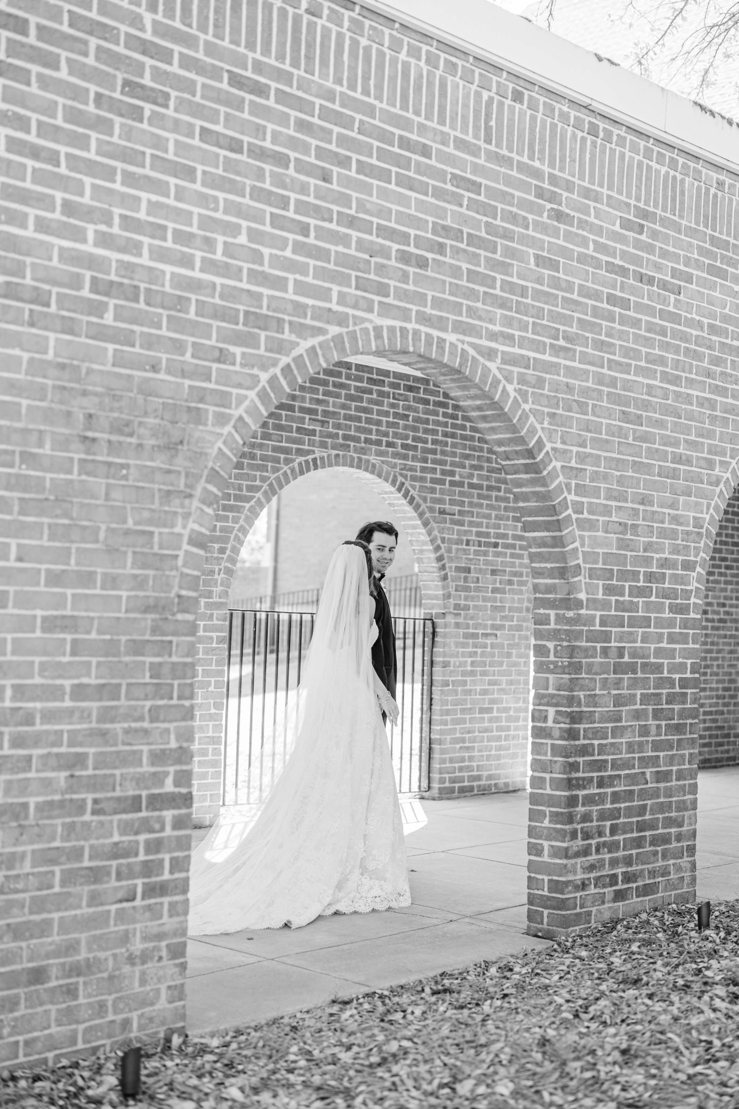 Sunlight streams through brick archways creating dramatic shadows on a wedding day.