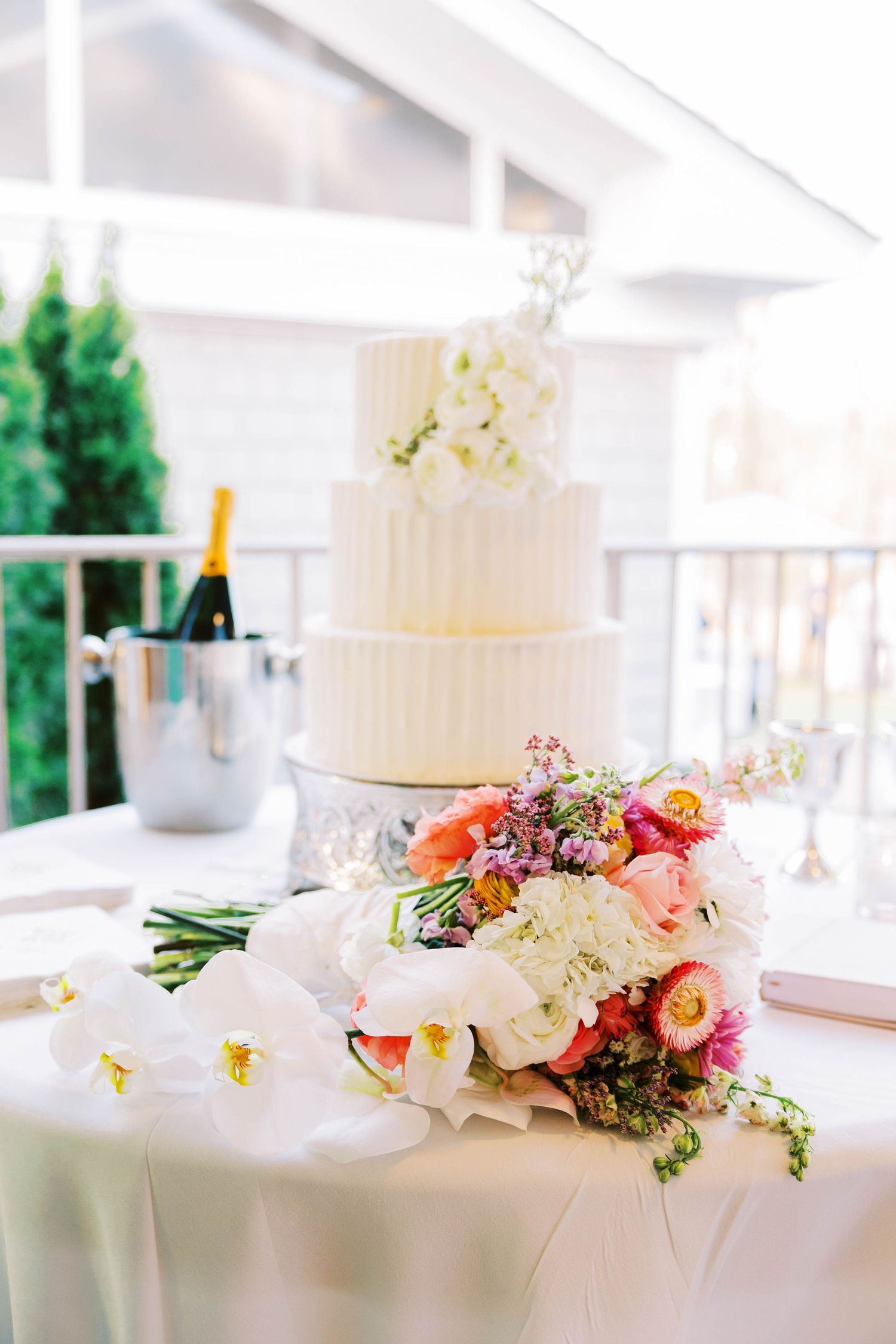 Elegant white wedding cake decorated with fresh flowers on display.