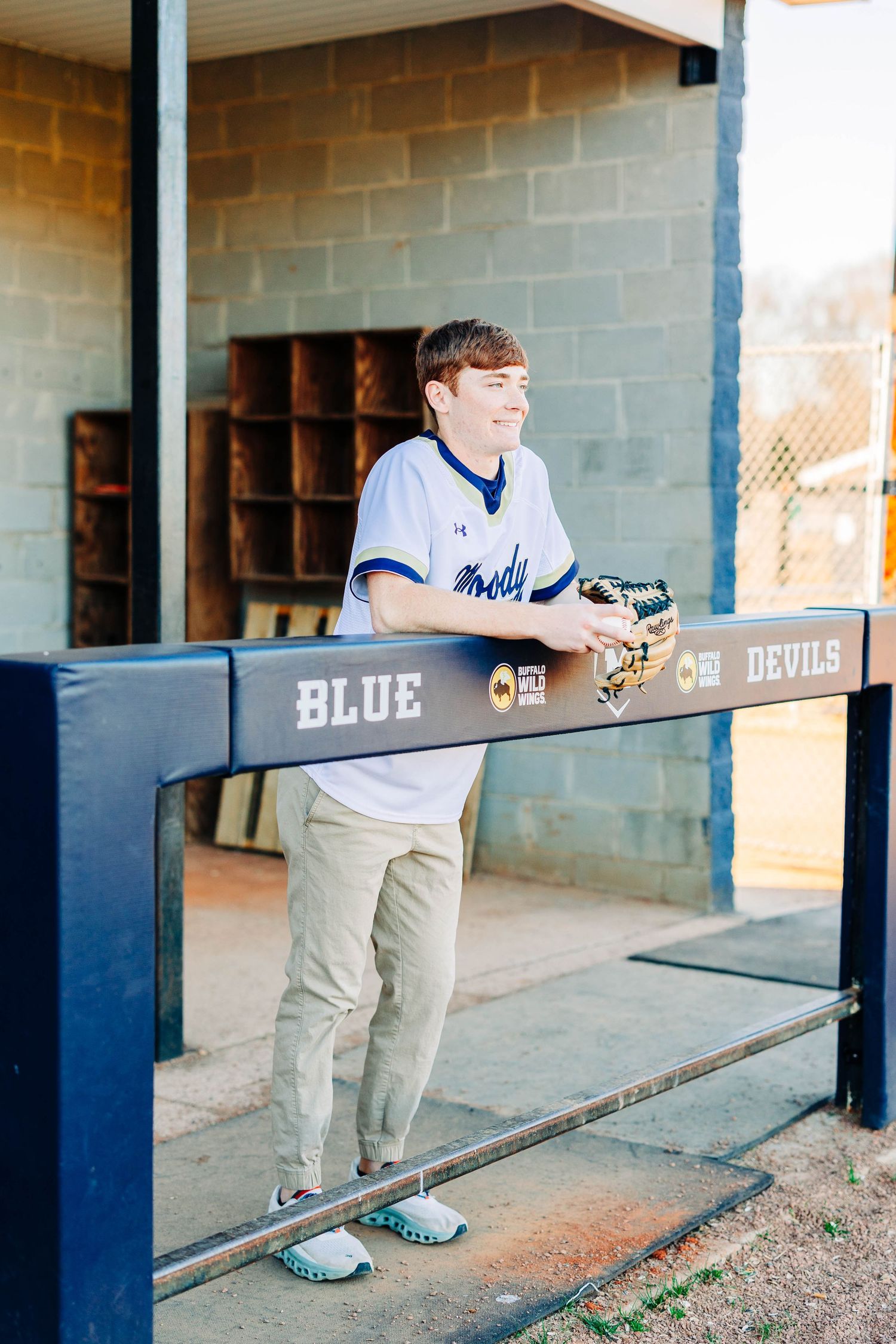 Sports dugout with blue railing and team logos displayed on wall.