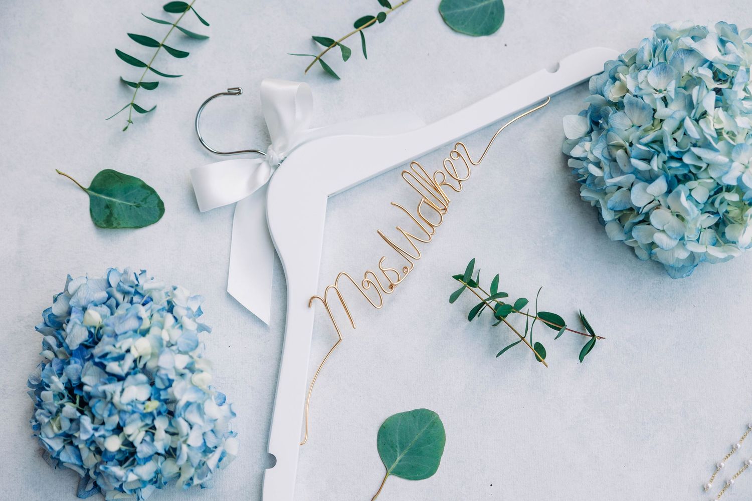 Delicate arrangement of blue hydrangeas and eucalyptus leaves on light background.