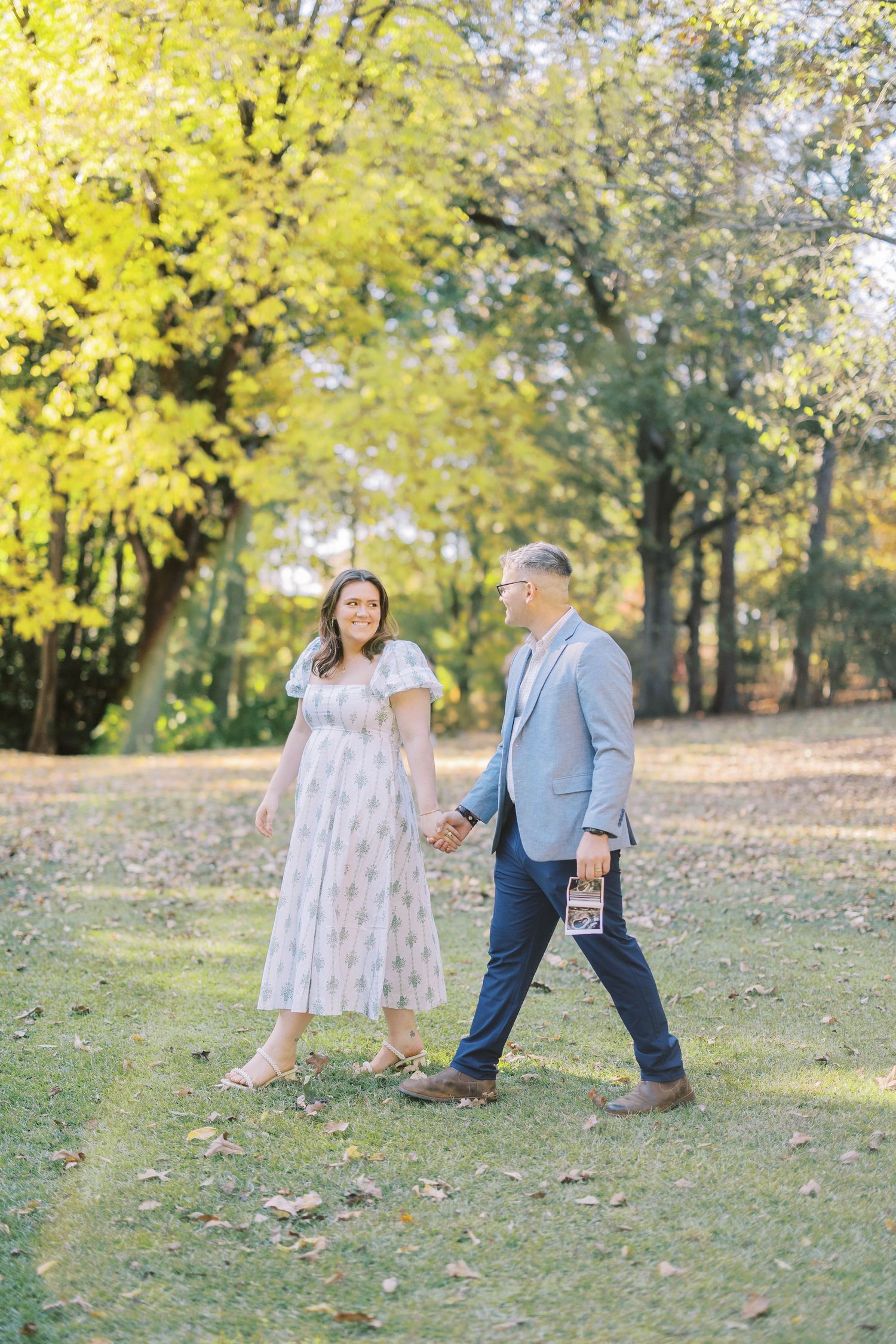 Couple enjoying a playful moment in a park with autumn foliage.