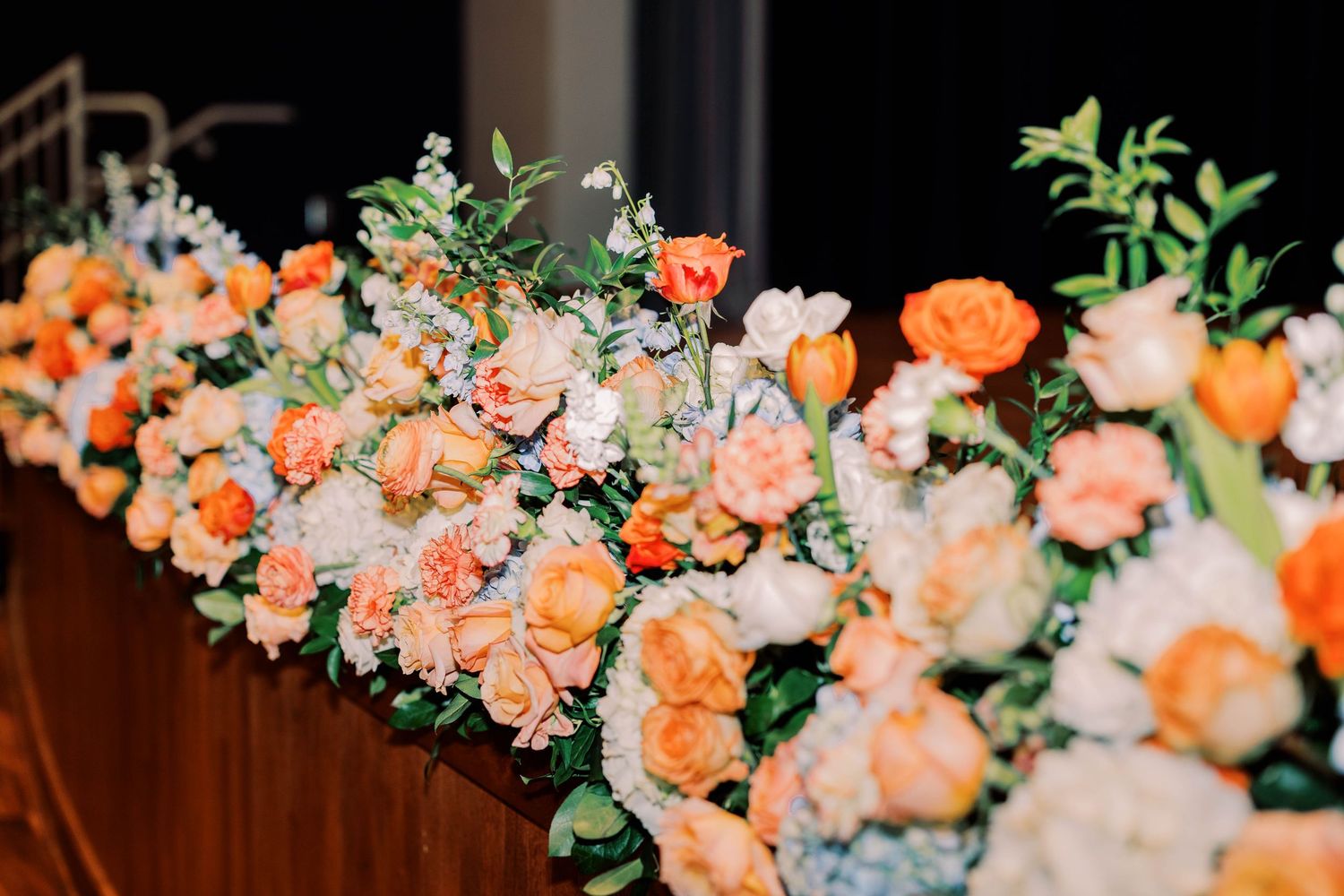 Peach and coral floral arrangements with greenery create an elegant wedding display.