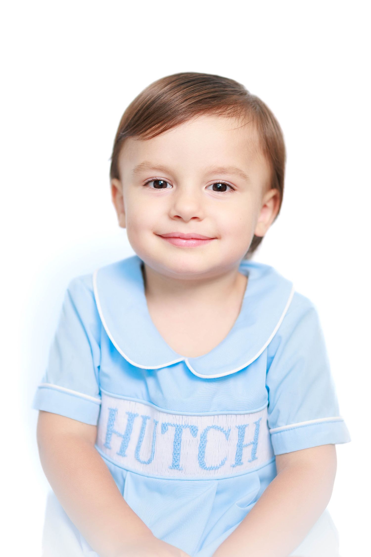 Young boy named Hutch smiling in a blue Peter Pan collar embroidered shirt on white background.