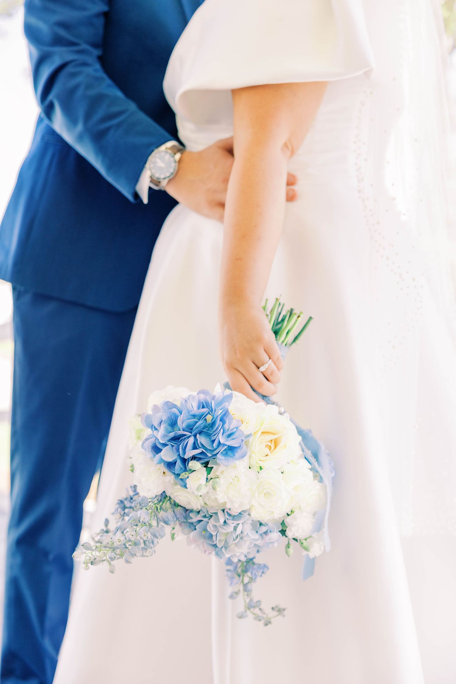 Close-up of a bridal bouquet featuring blue hydrangeas and white flowers.