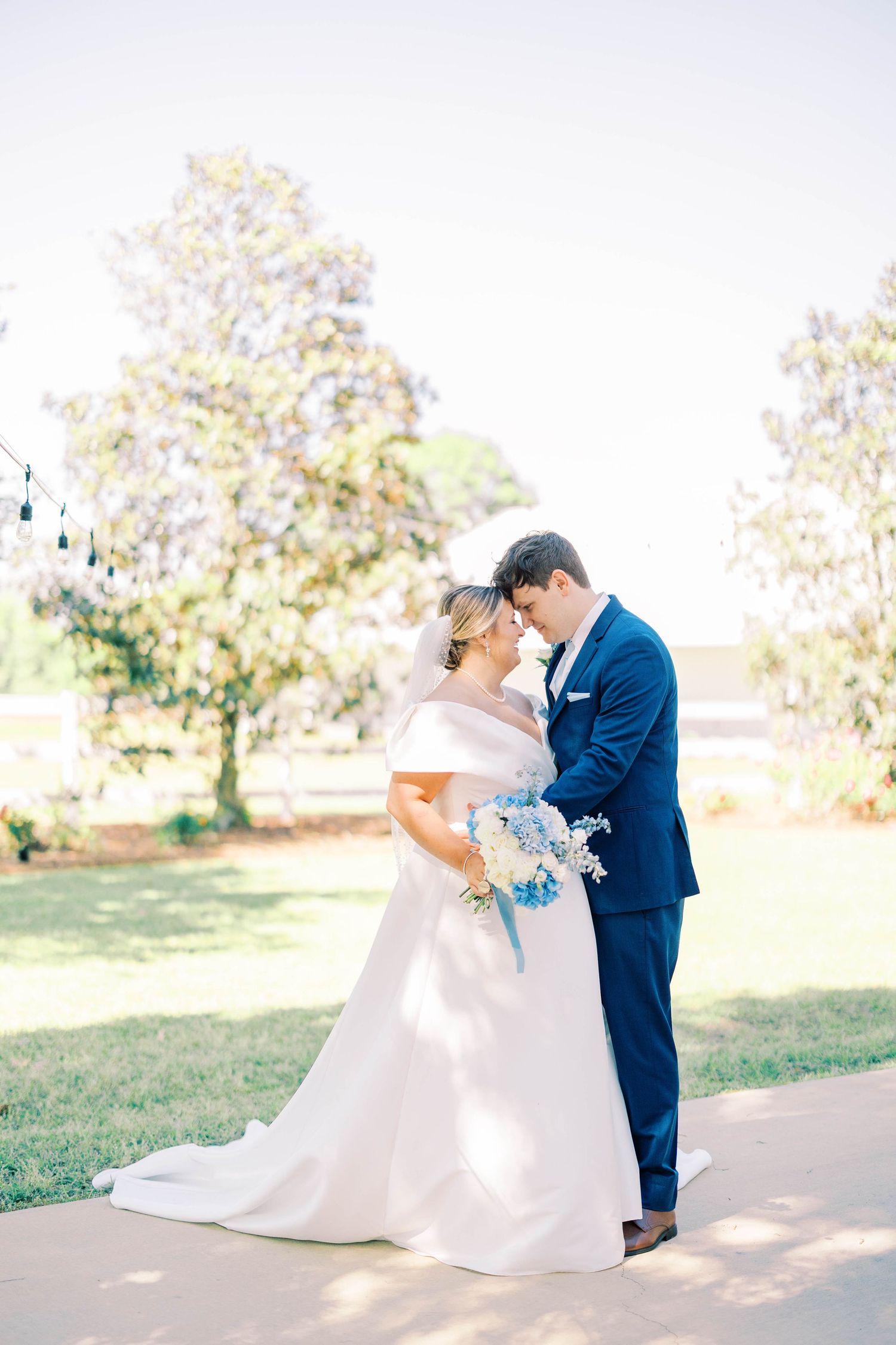 Romantic outdoor wedding portraits with couple in white dress and navy suit.