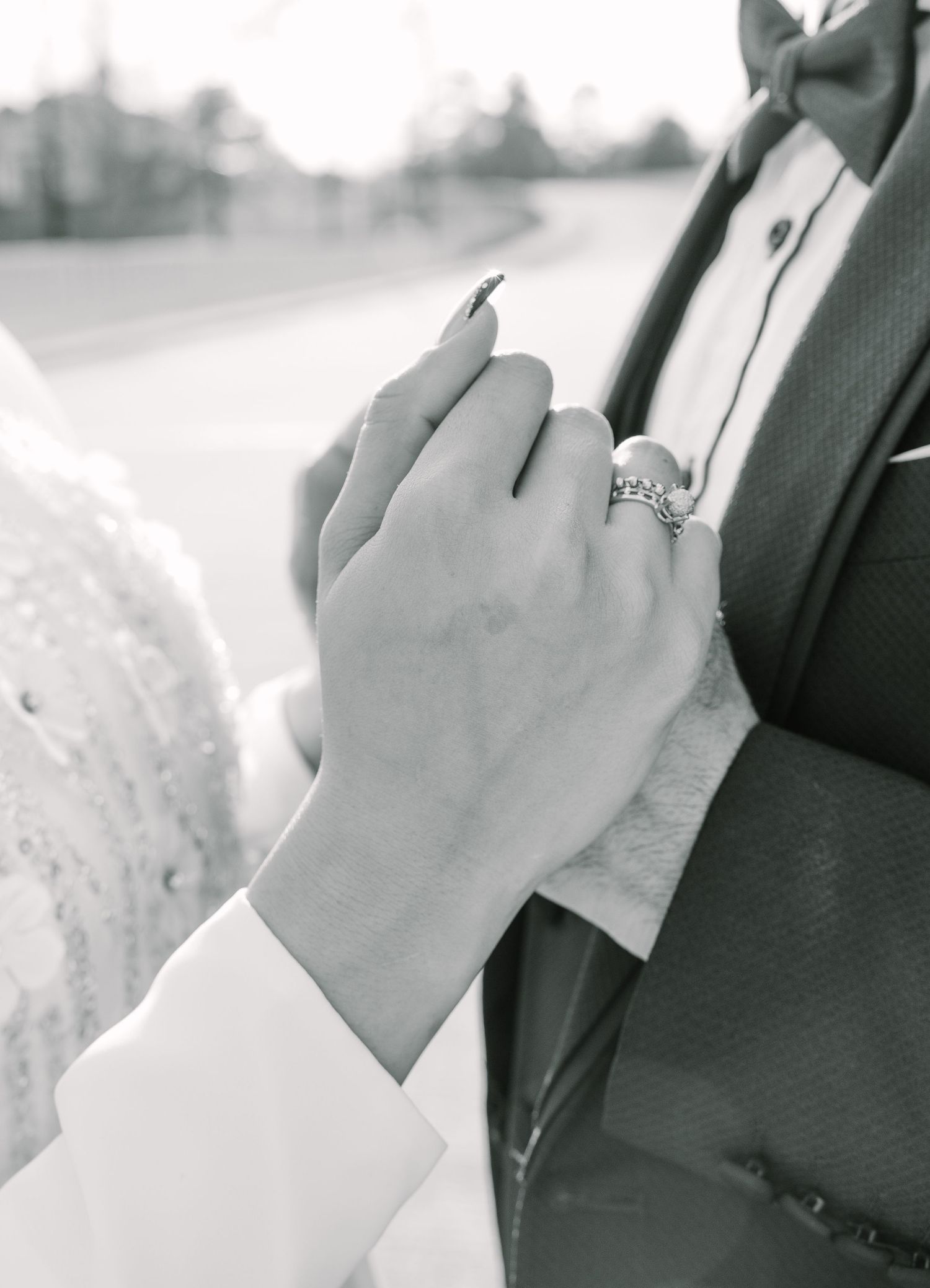 Close-up of hands wearing wedding rings in black and white.