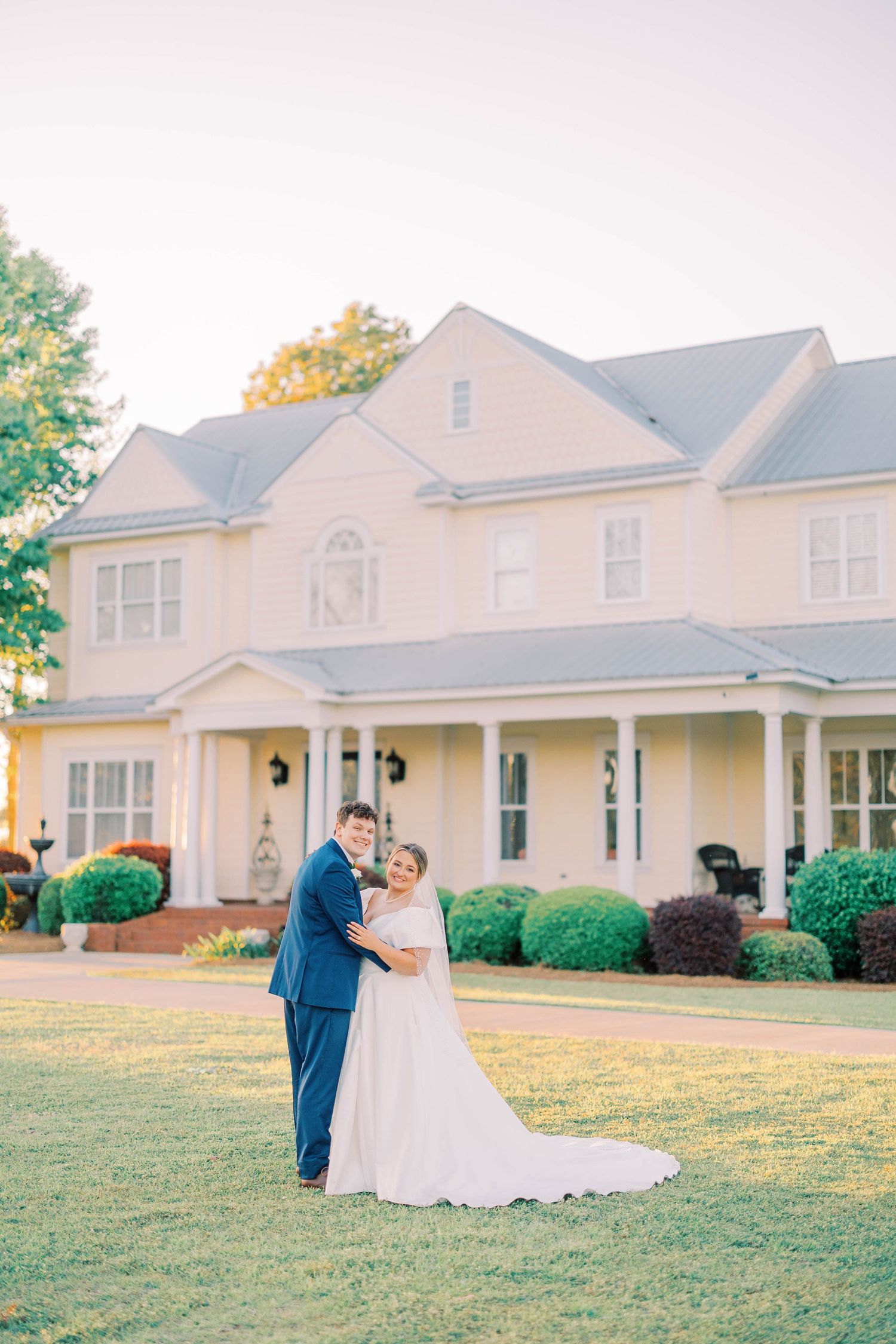 Elegant wedding photos in front of a grand white colonial style house.