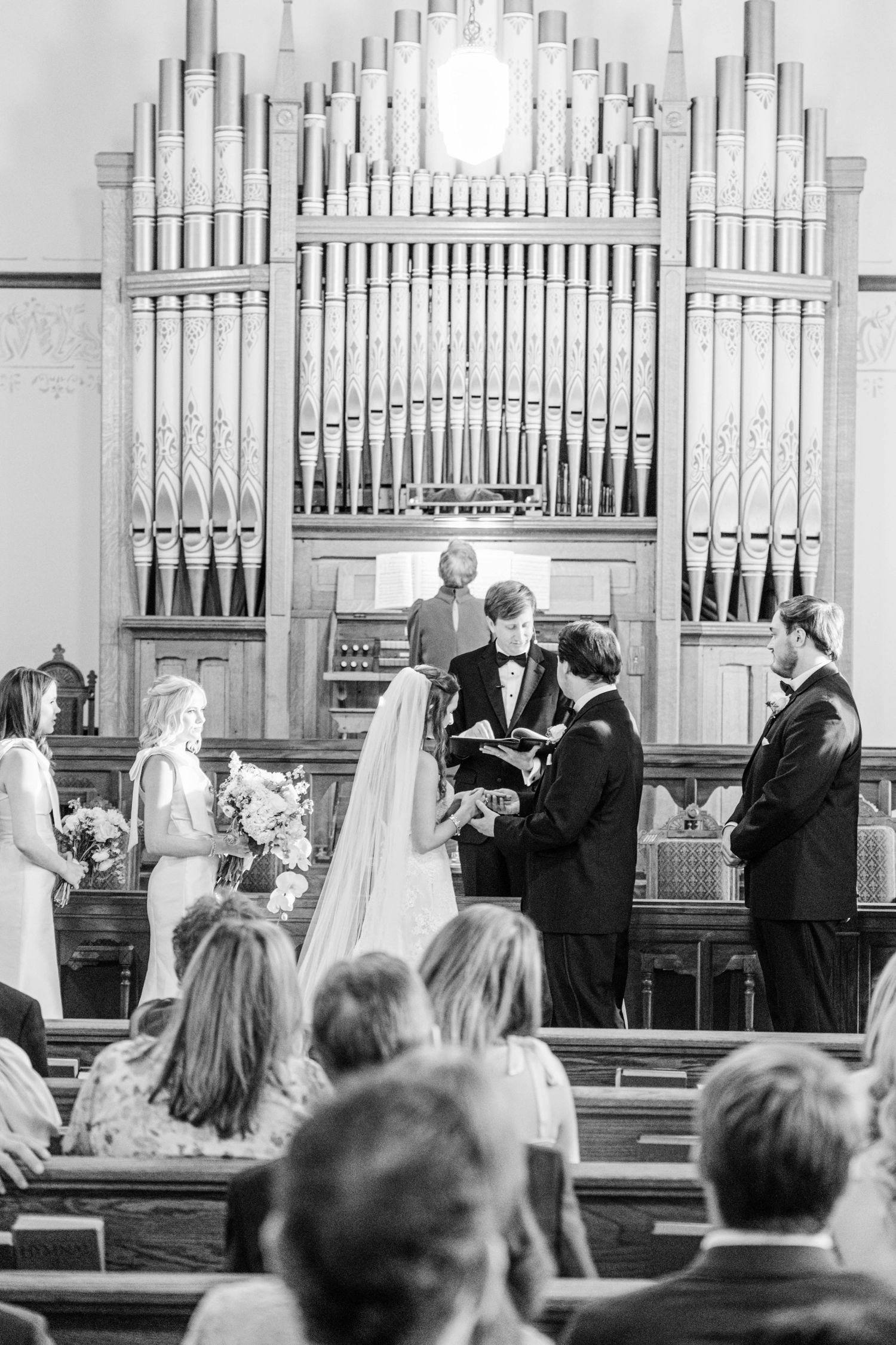 Black and white photo of a traditional church wedding ceremony with pipe organ in the background.