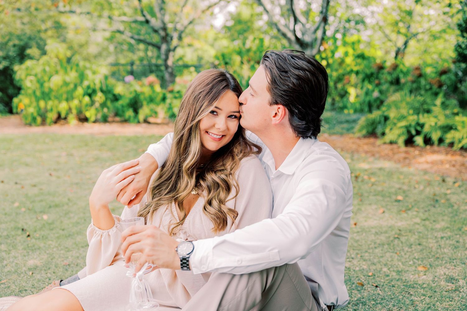 A romantic outdoor engagement moment captured in soft, warm lighting.