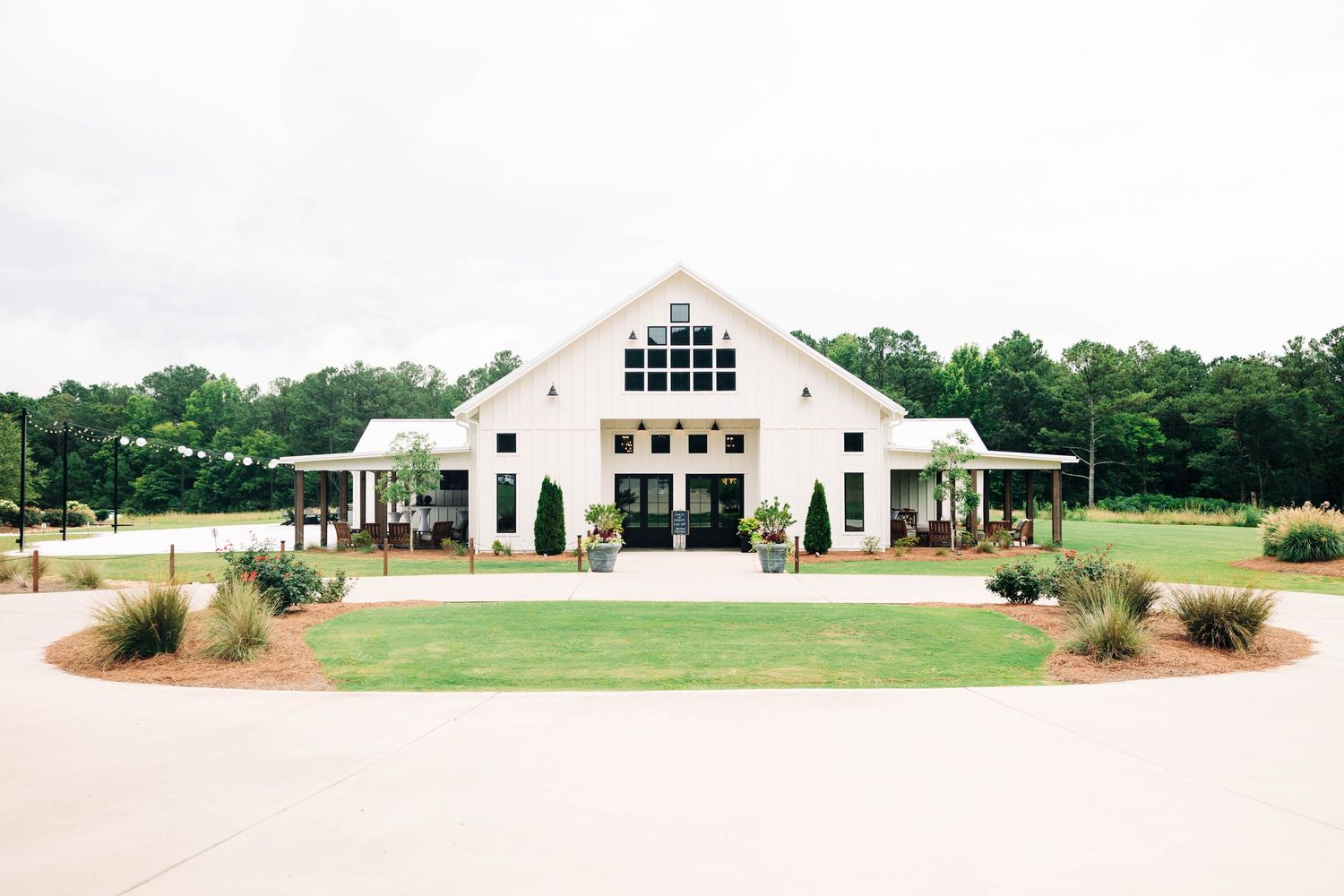 Panoramic view of a white modern farmhouse style wedding venue with manicured grounds.