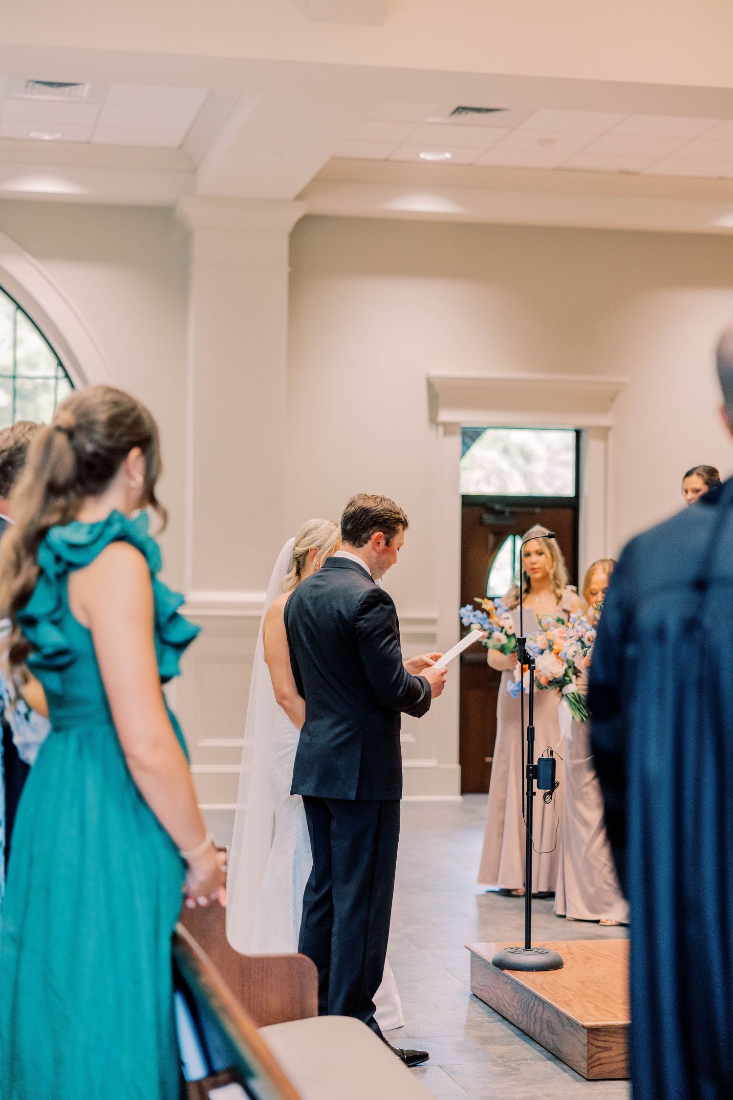 Wedding party in teal bridesmaid dresses preparing in a bright indoor venue.