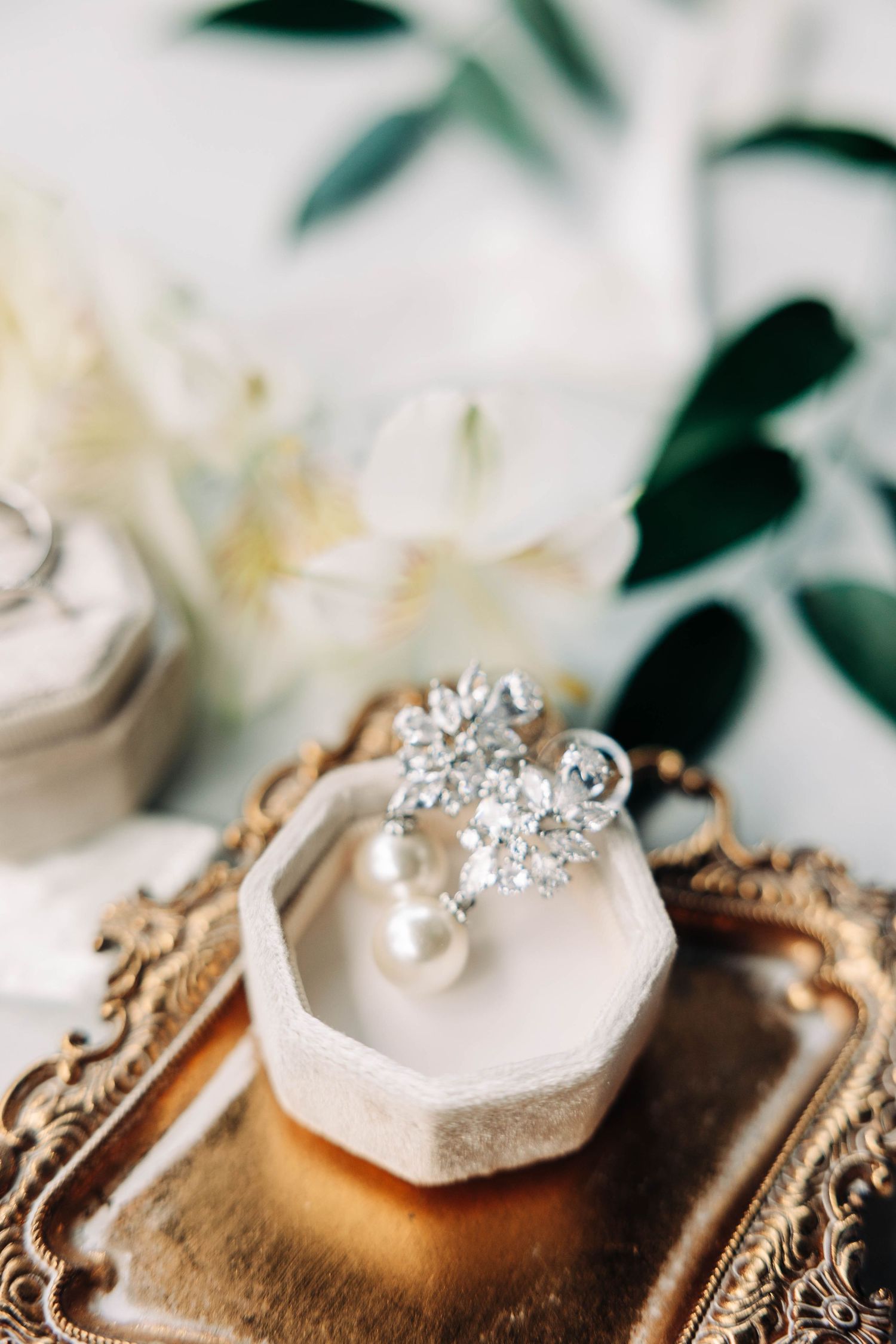 Wedding rings and pearl accessories displayed on vintage silver tray.