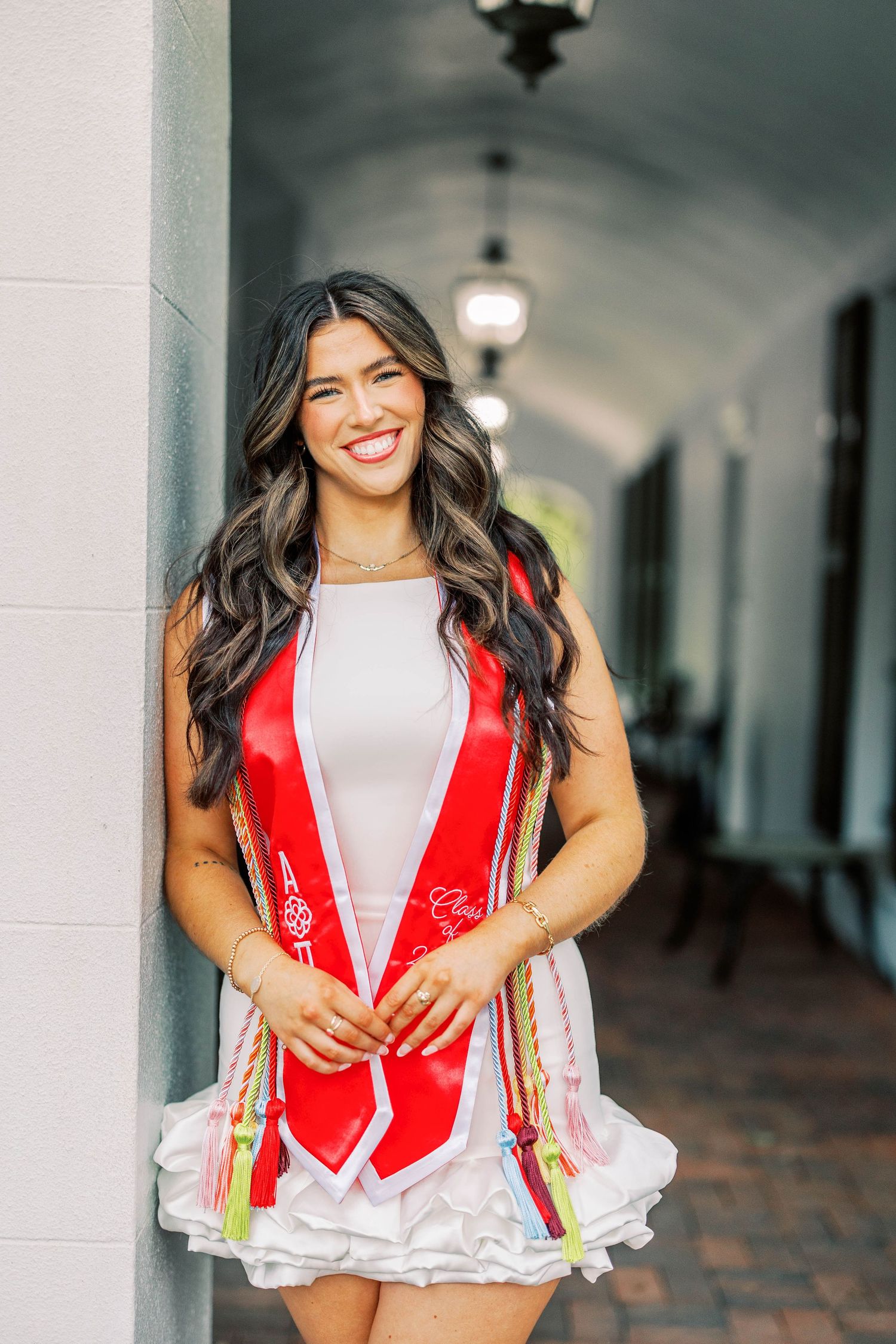 Person wearing red and white cheerleading uniform posing under covered walkway.