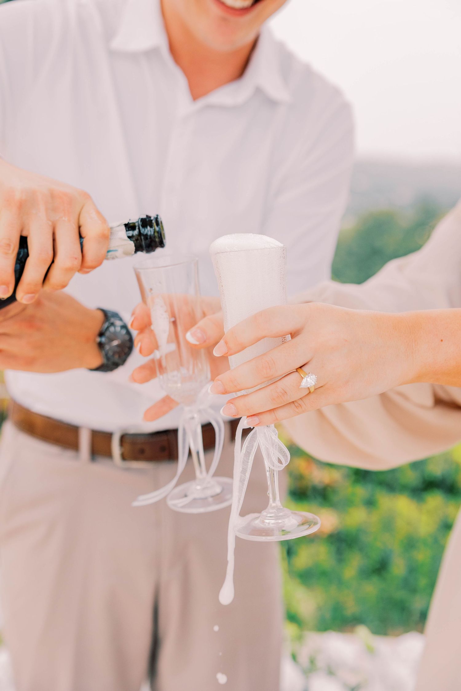 Hands pouring champagne into glasses during a celebration outdoors.