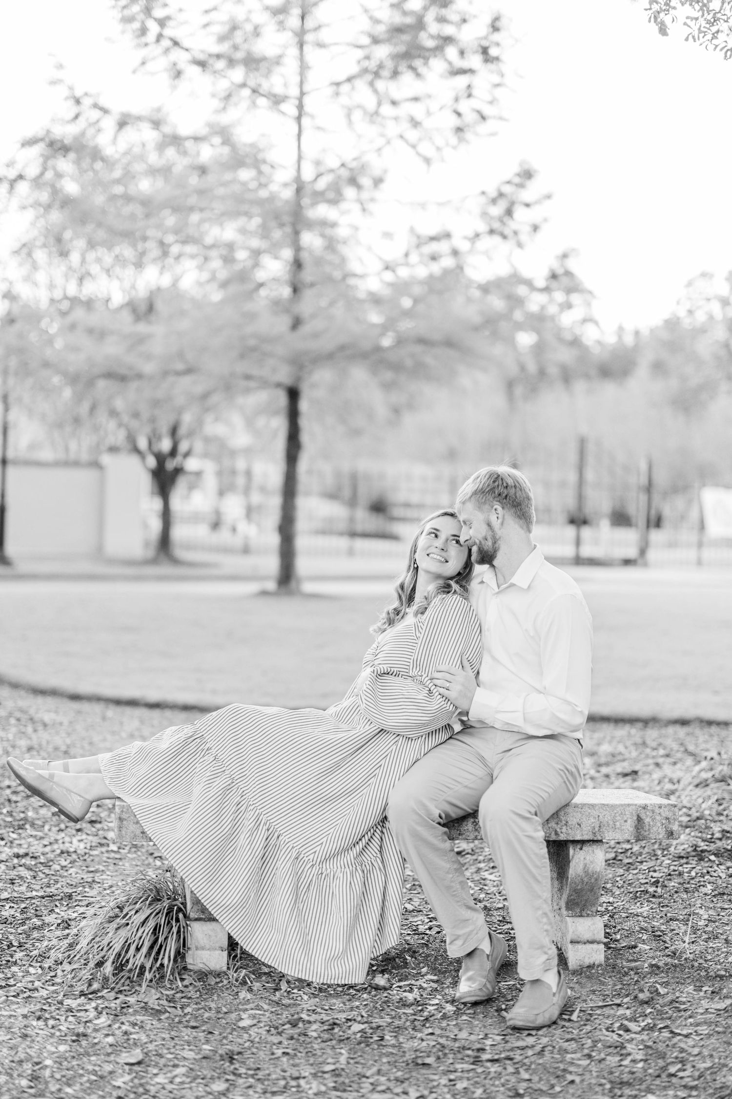 A couple sits together on fallen leaves in black and white photography.