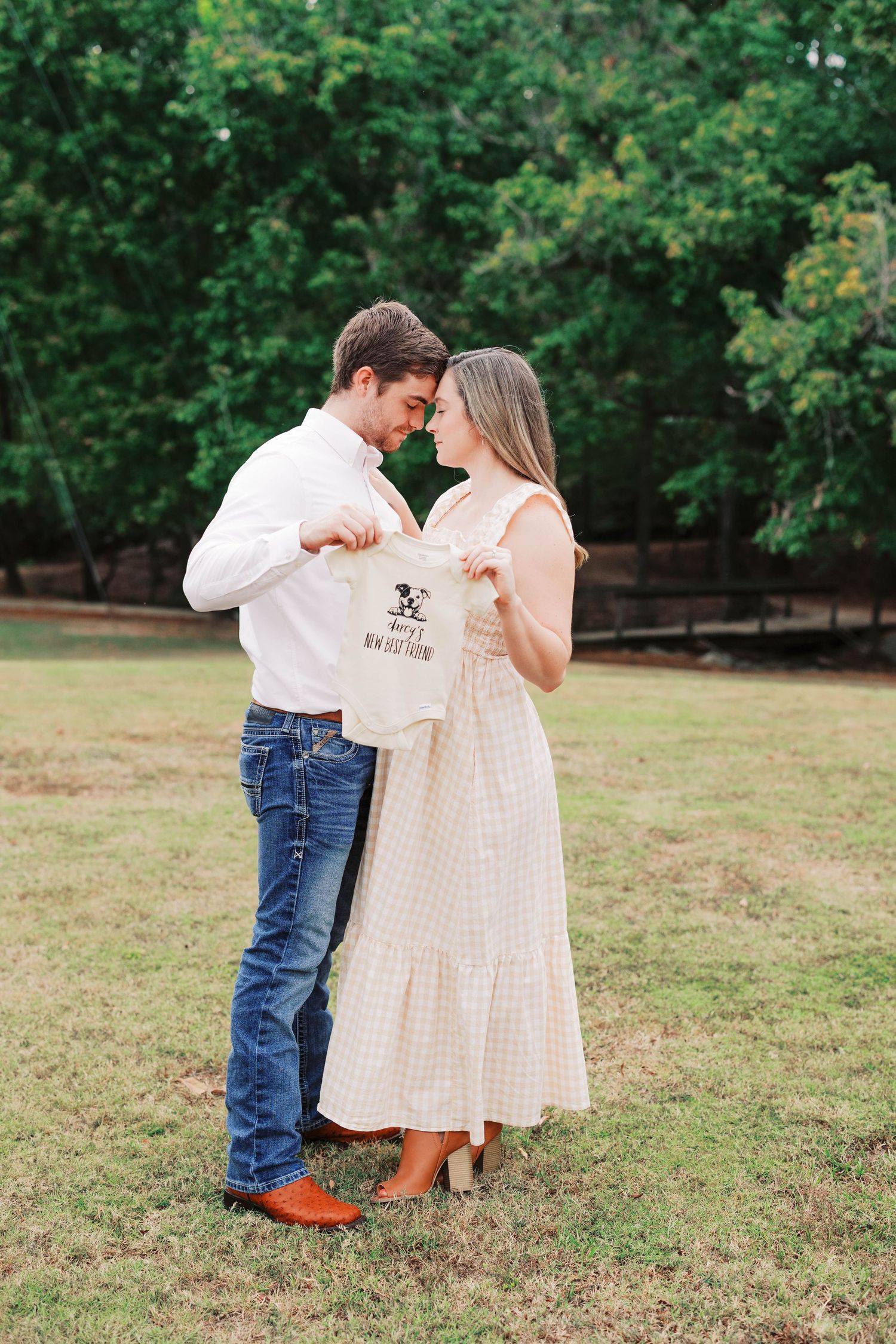 A couple dances together in a grassy field, with the woman wearing a flowing white dress.