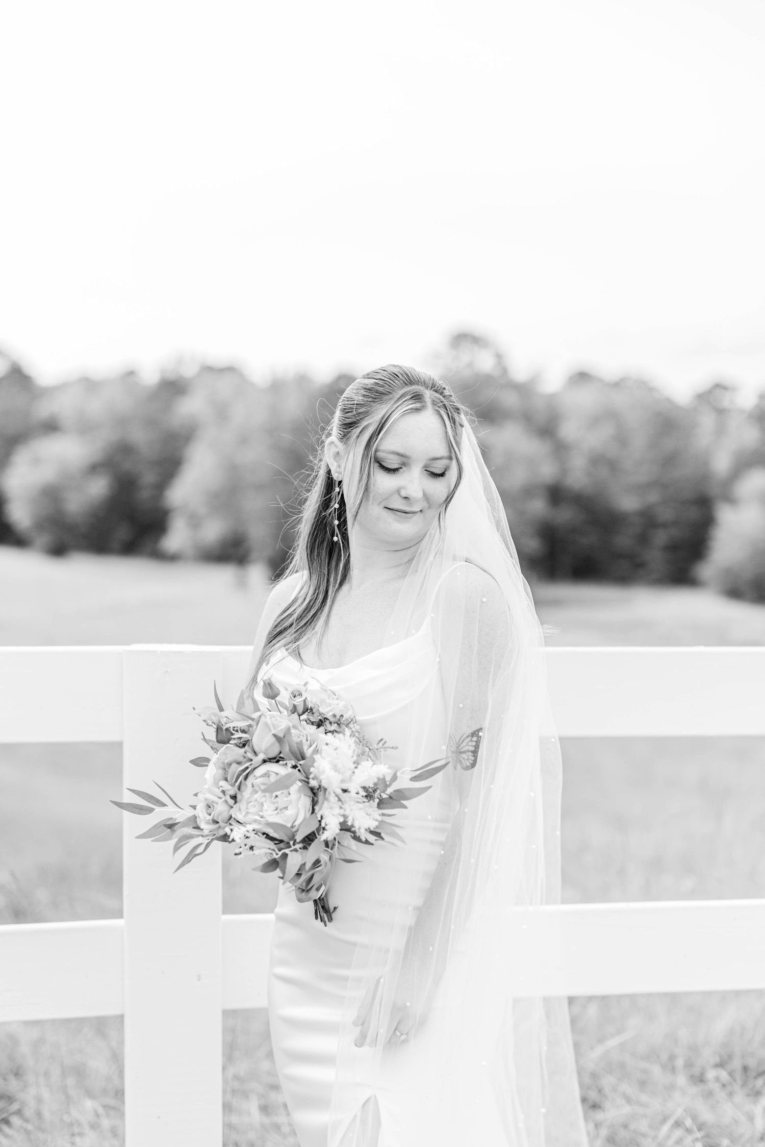 Elegant bridal portraits in soft natural light against white fence backdrop.