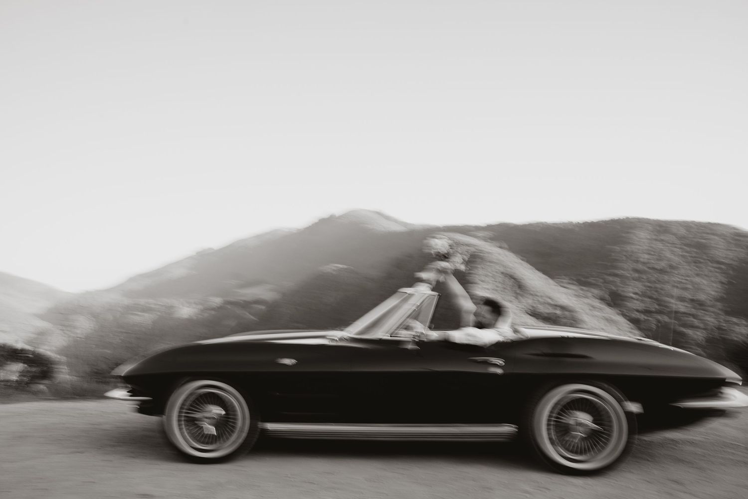 A sleek black vintage convertible sports car photographed in motion from multiple angles against a blurred background.