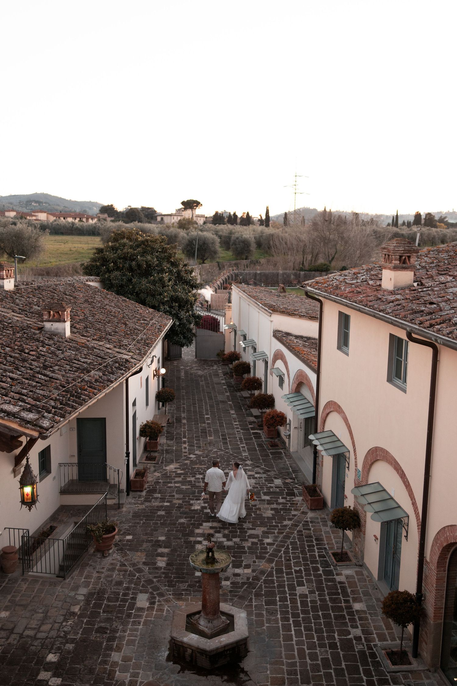 Panoramic view of a historic Italian village street with traditional stone buildings and terracotta roofs under cloudy skies.