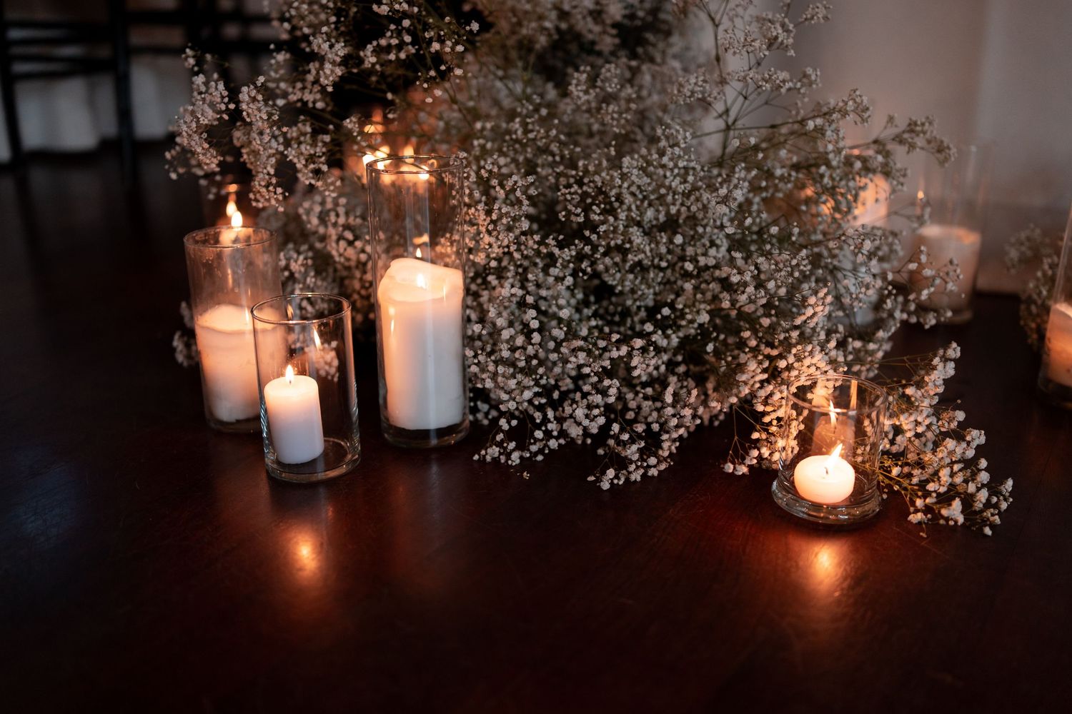 White baby's breath flowers and glowing candles create an elegant romantic atmosphere in a dark room.