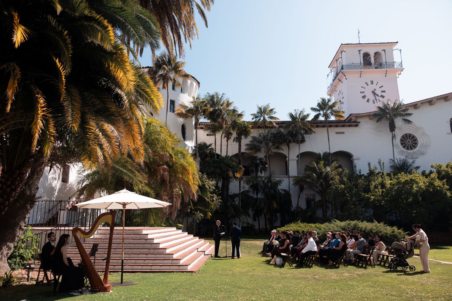 A scenic view of a Spanish-style church with palm trees and white stucco buildings along a coastal pathway.