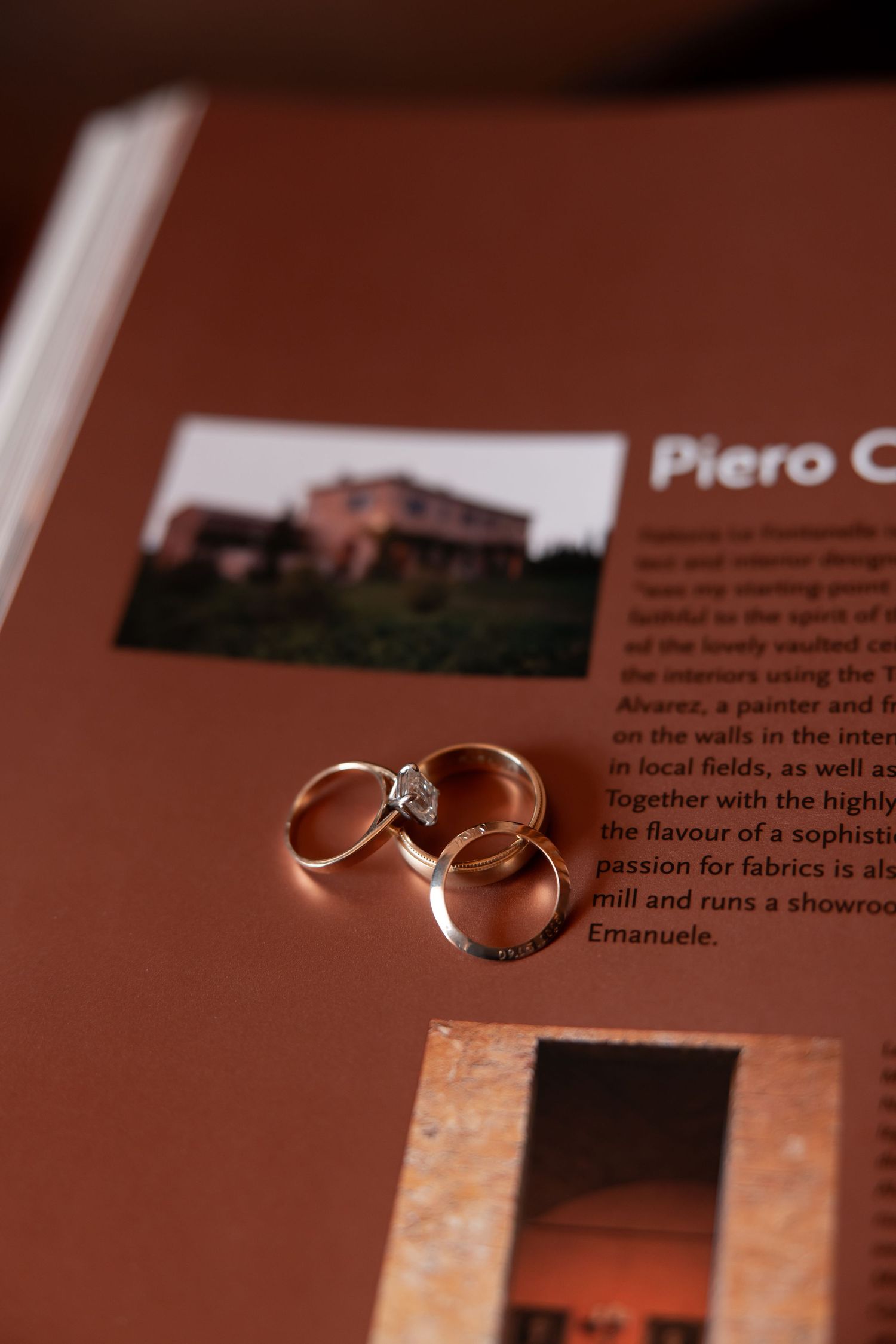 Two elegant wedding rings sit atop a brown textured surface with text visible in the background.