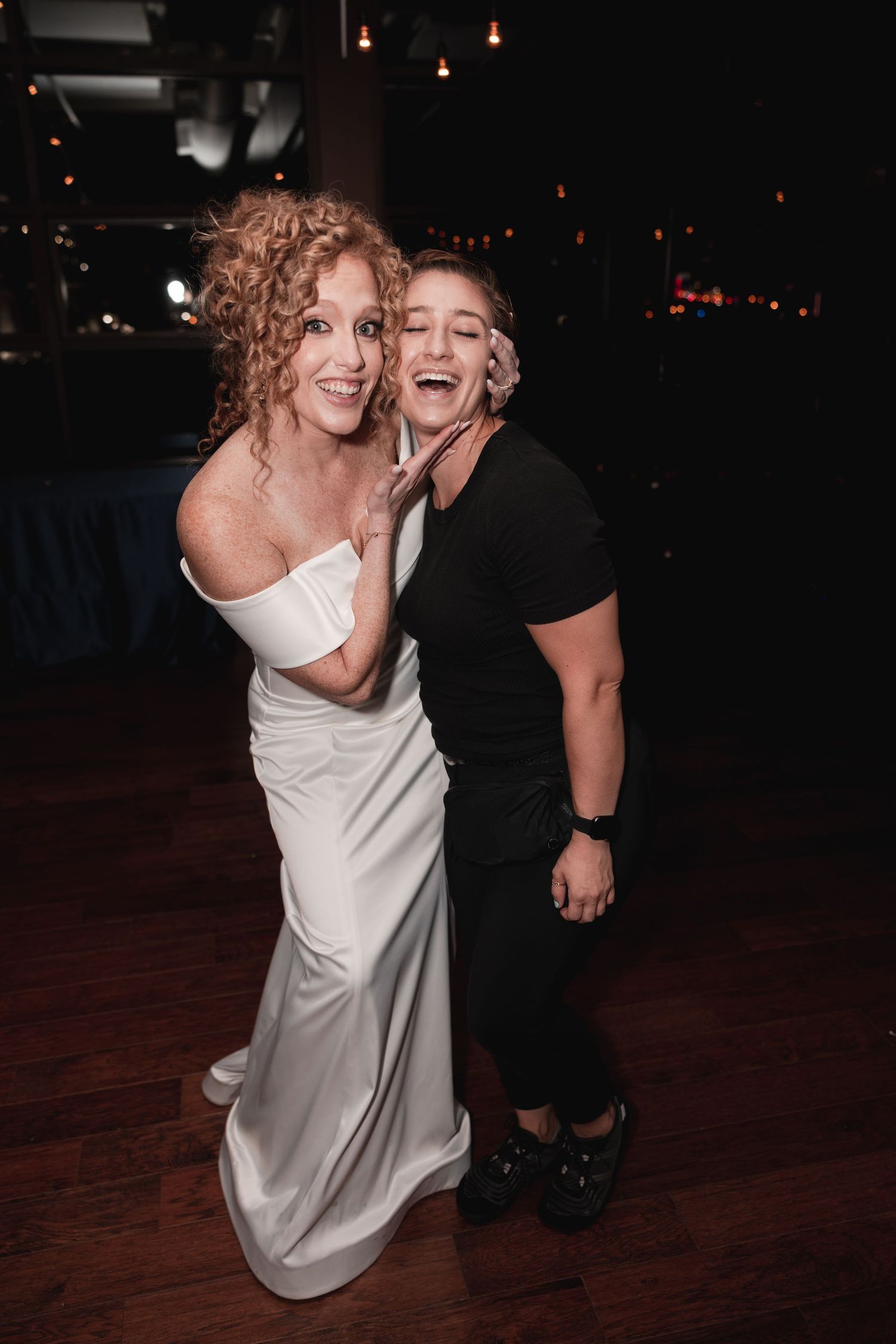 Two people in black and white attire share a joyful moment dancing together on a dark wooden dance floor.
