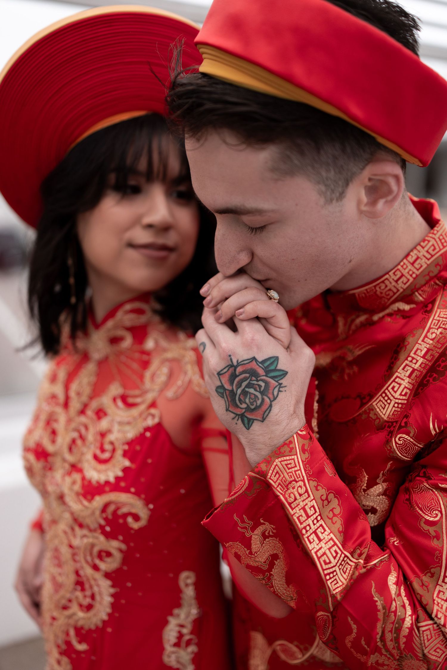 A couple in traditional red Chinese wedding attire share an intimate moment during their celebration.
