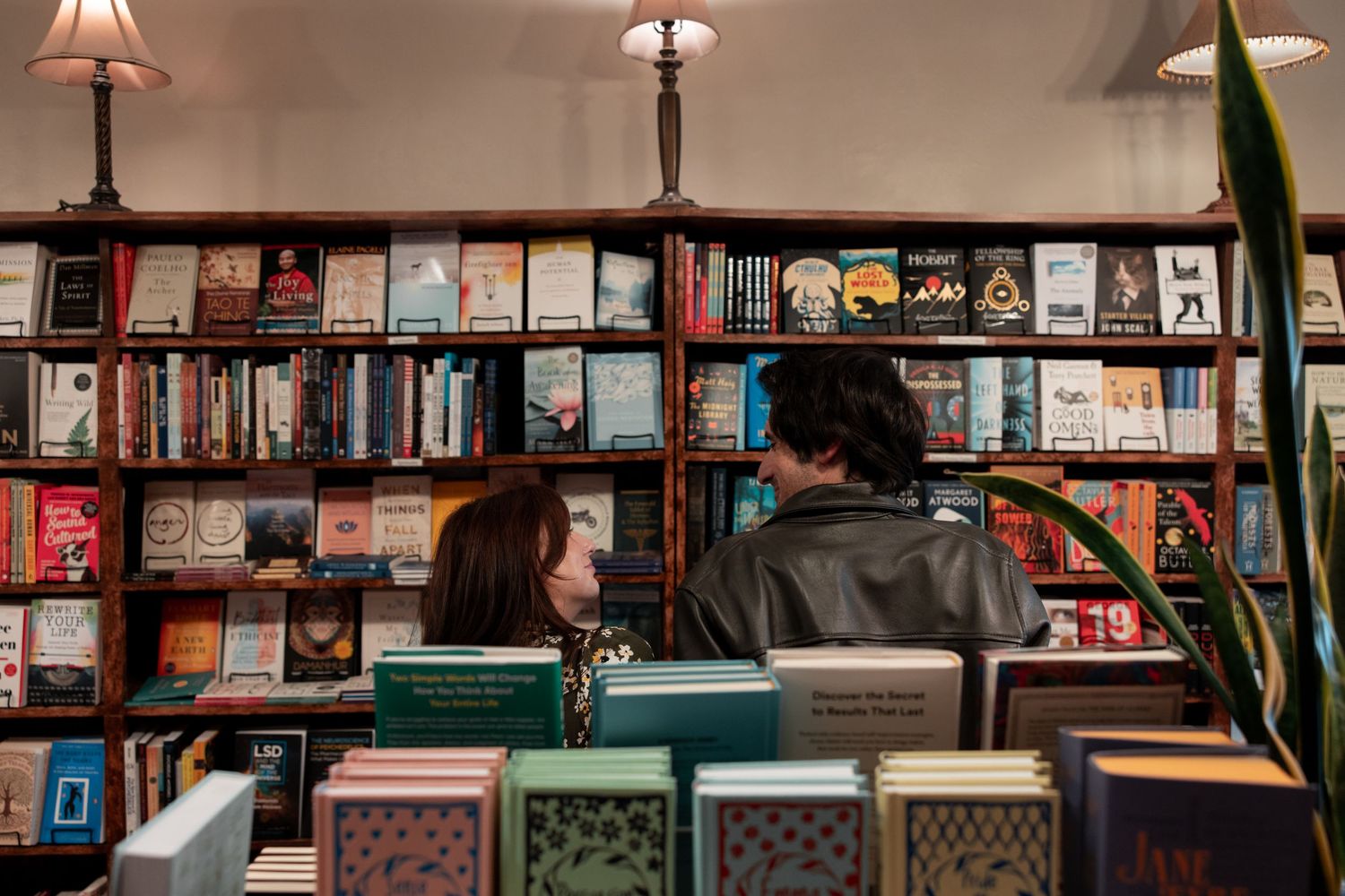 A cozy bookstore interior with wooden shelves filled with books and warm lighting from pendant lamps overhead.