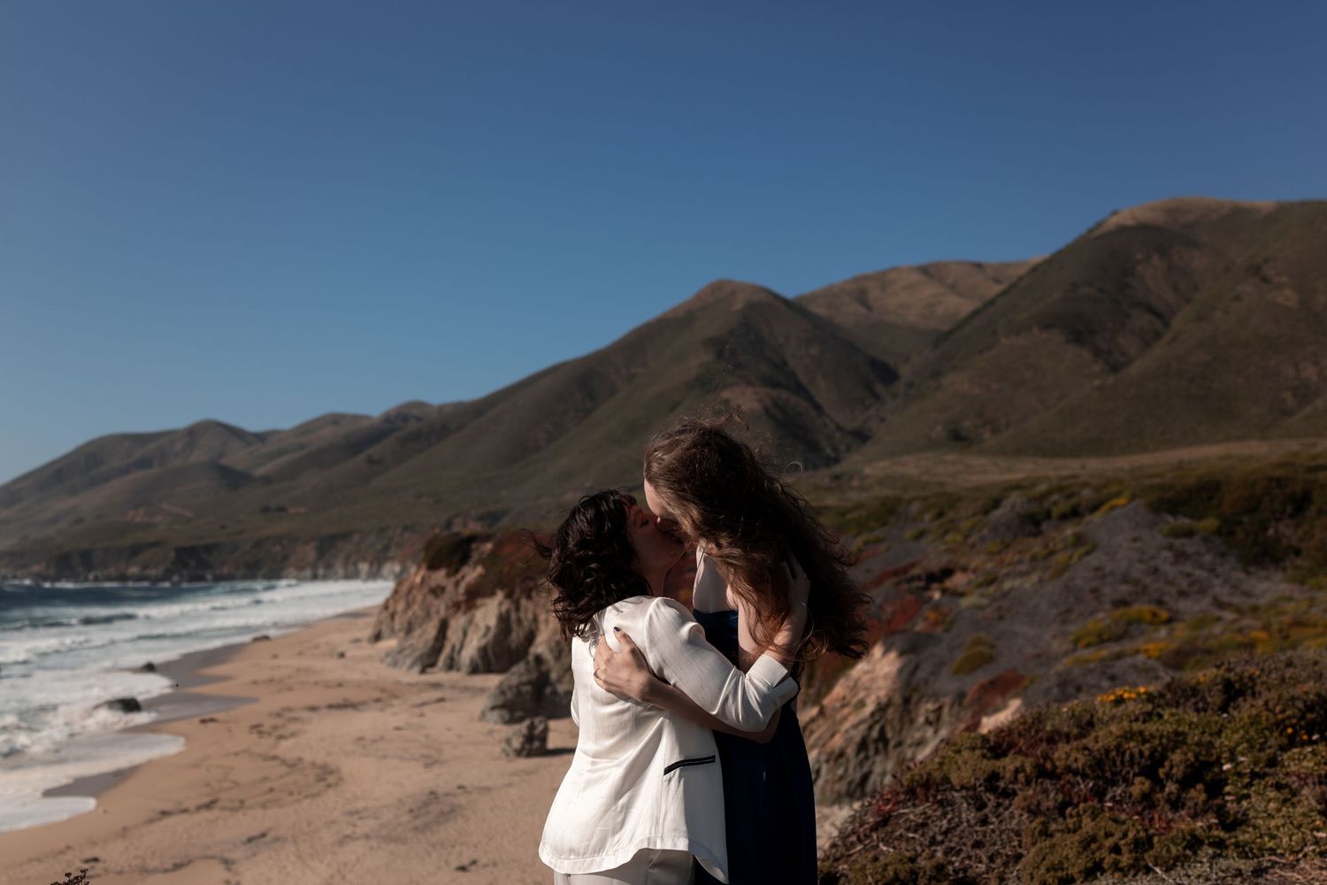 Scenic coastal landscape with rugged cliffs and ocean waves crashing against the rocky California shoreline.