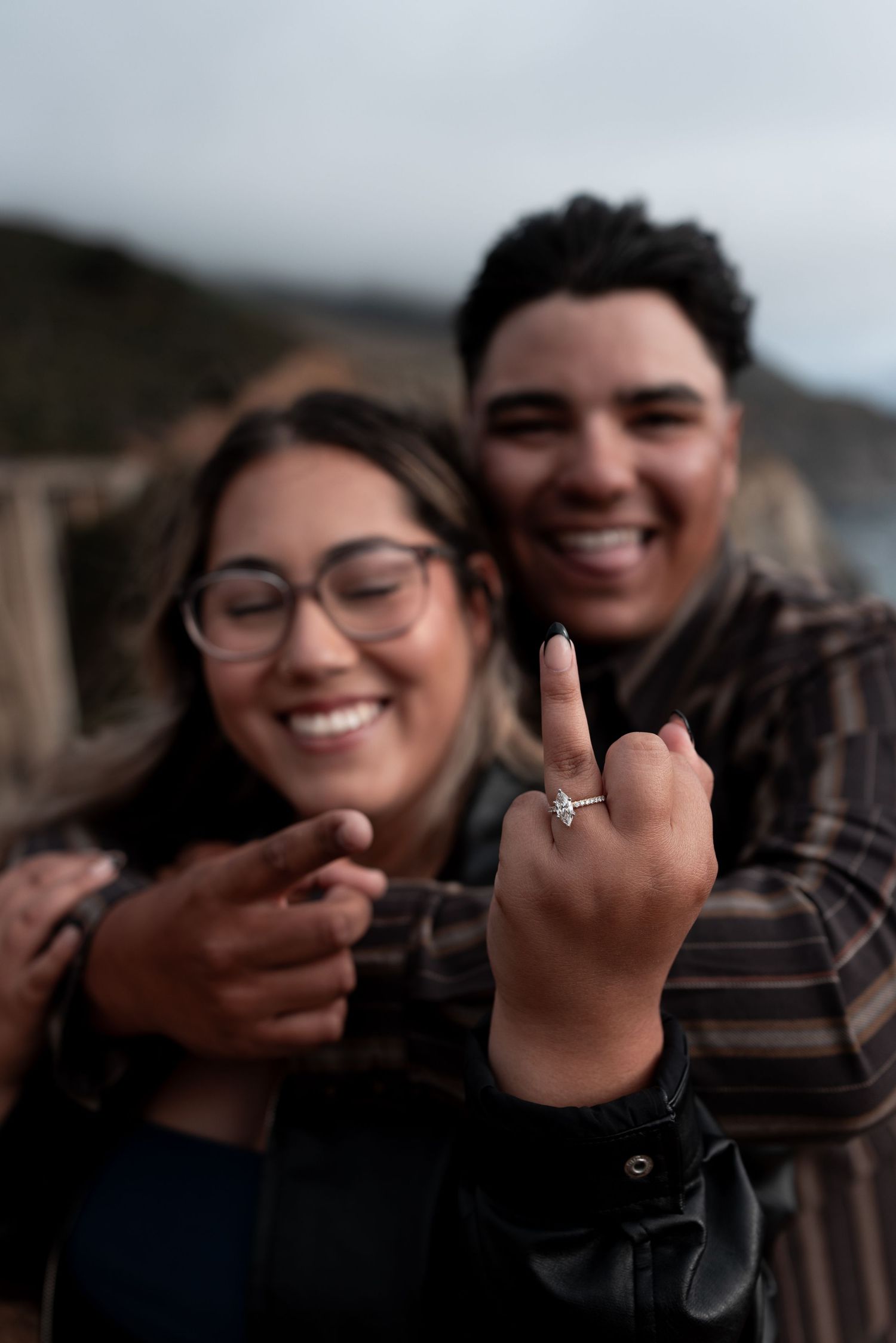 A couple laughs together while showing their engagement ring in a series of candid outdoor photos.