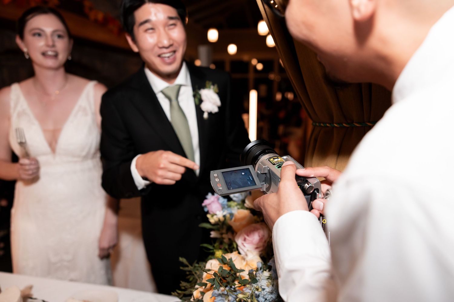 Wedding reception guests dance and celebrate on a dance floor illuminated by warm glowing lights.