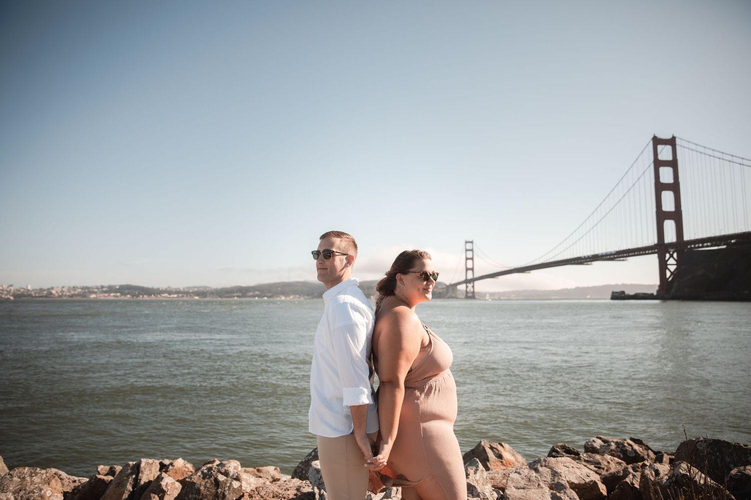A romantic engagement photoshoot overlooking the iconic Golden Gate Bridge in San Francisco Bay on a sunny day.