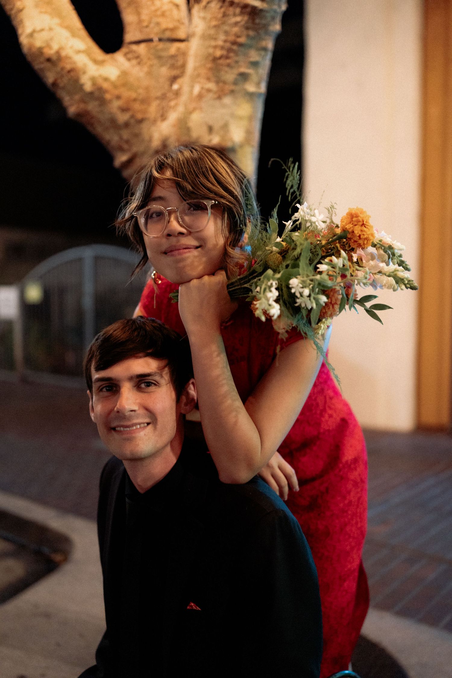 A couple in black and red outfits share playful moments together in a series of connected photos.