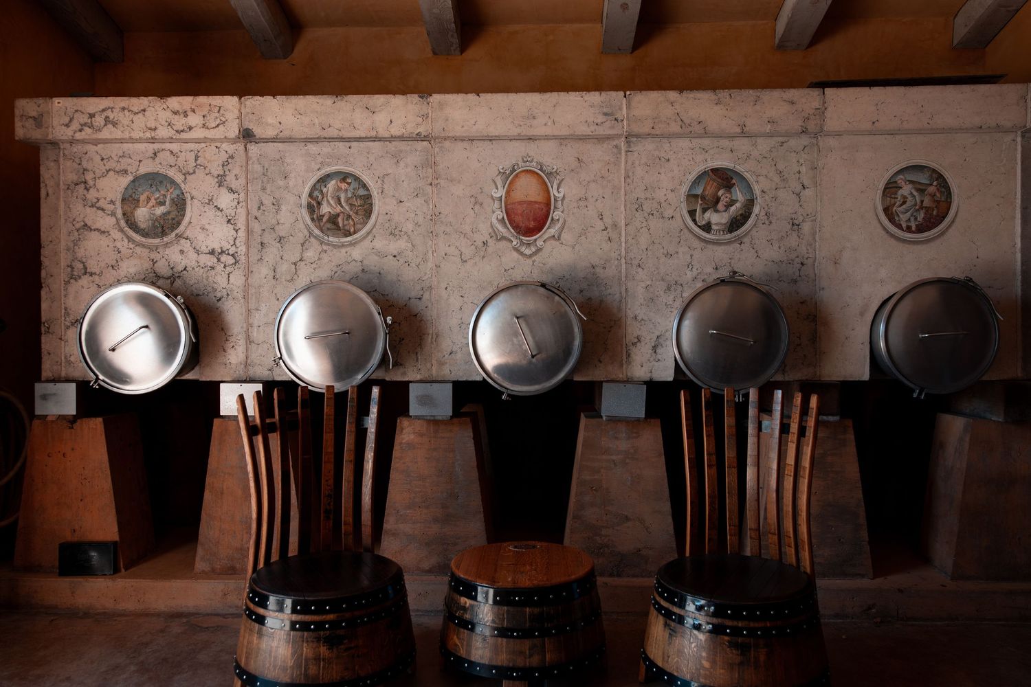 A rustic wooden ceiling with exposed beams and hanging metal light fixtures in a restaurant or bar setting.